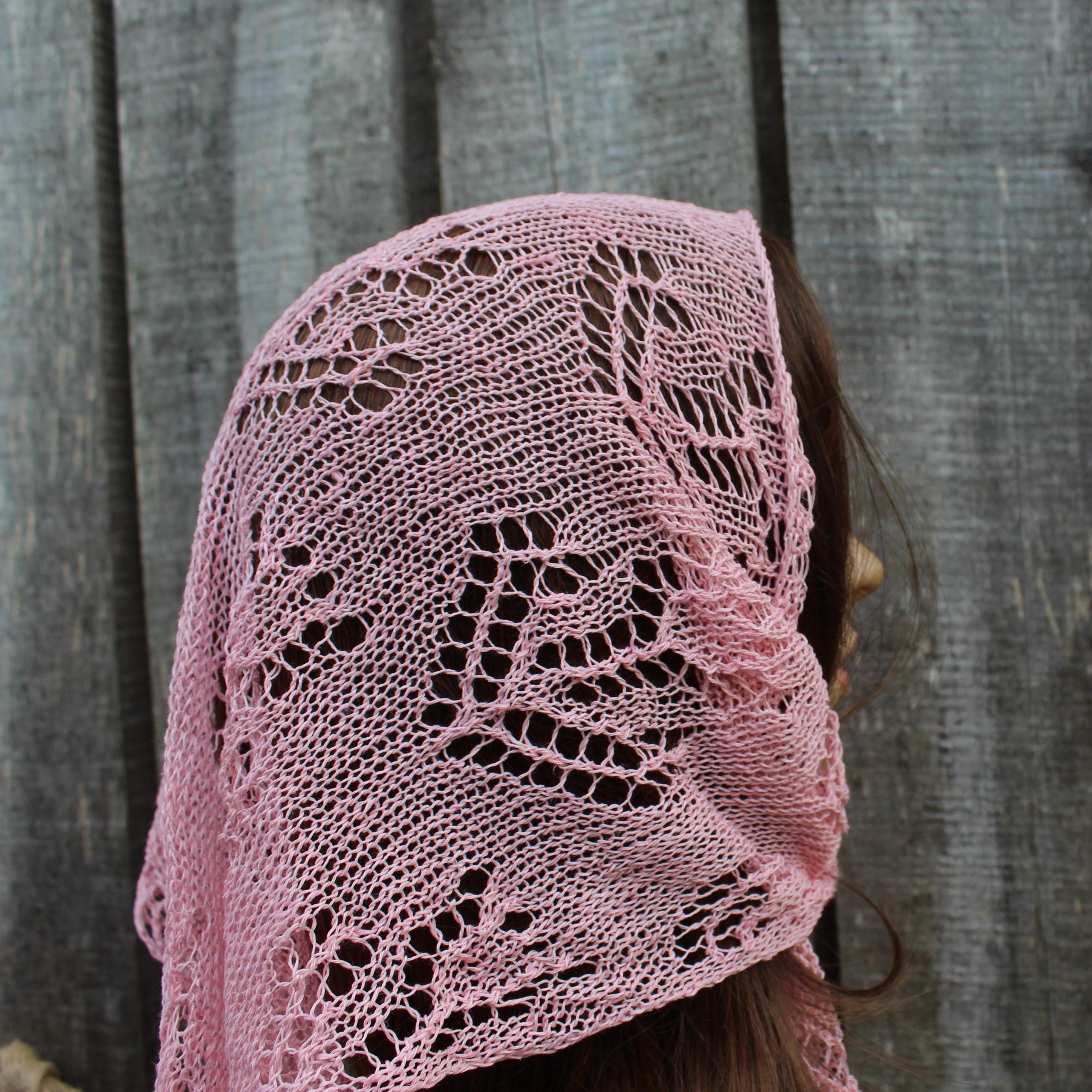 Pink lace kerchief draped over a person against a wooden background