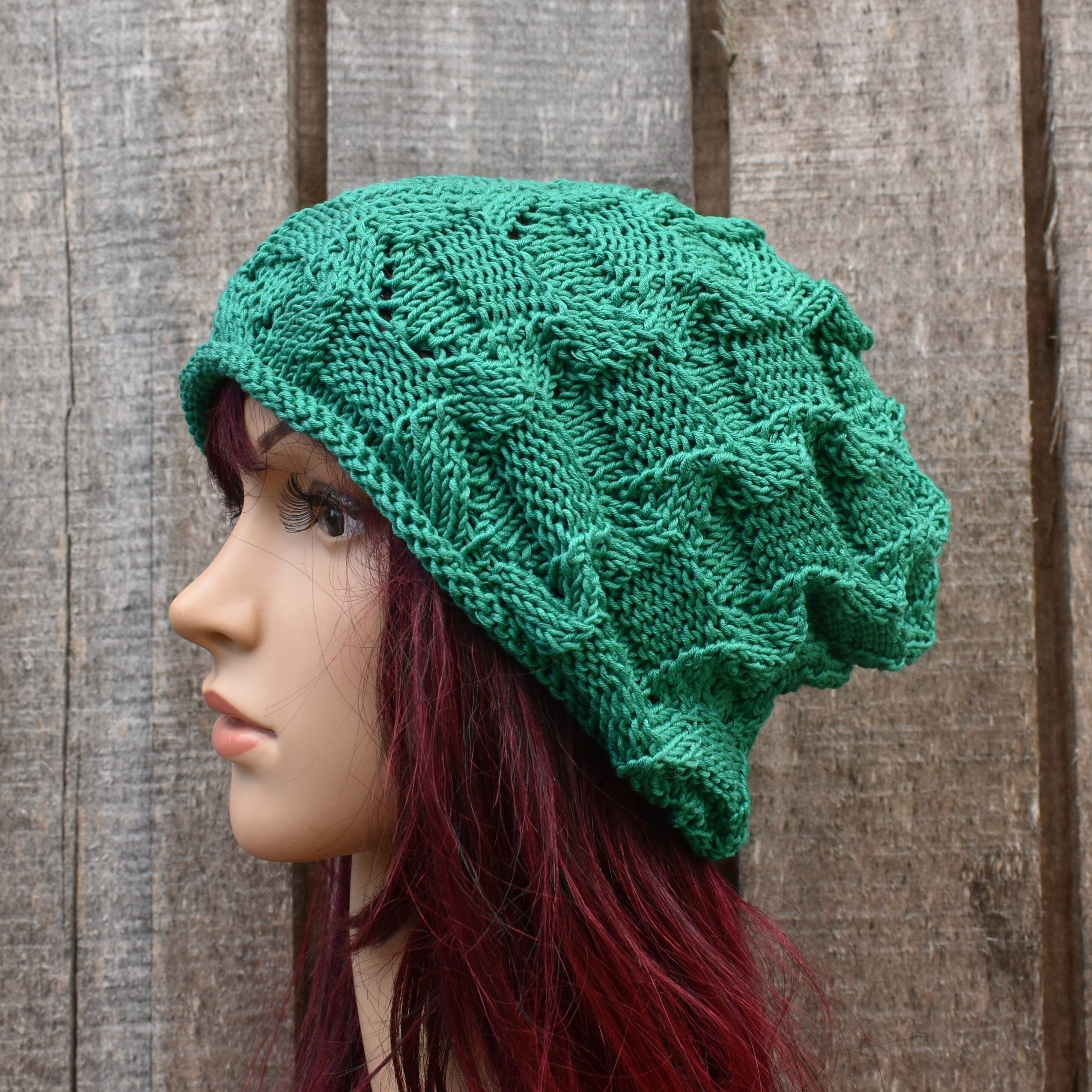 Green knitted hat on a mannequin head against a wooden background