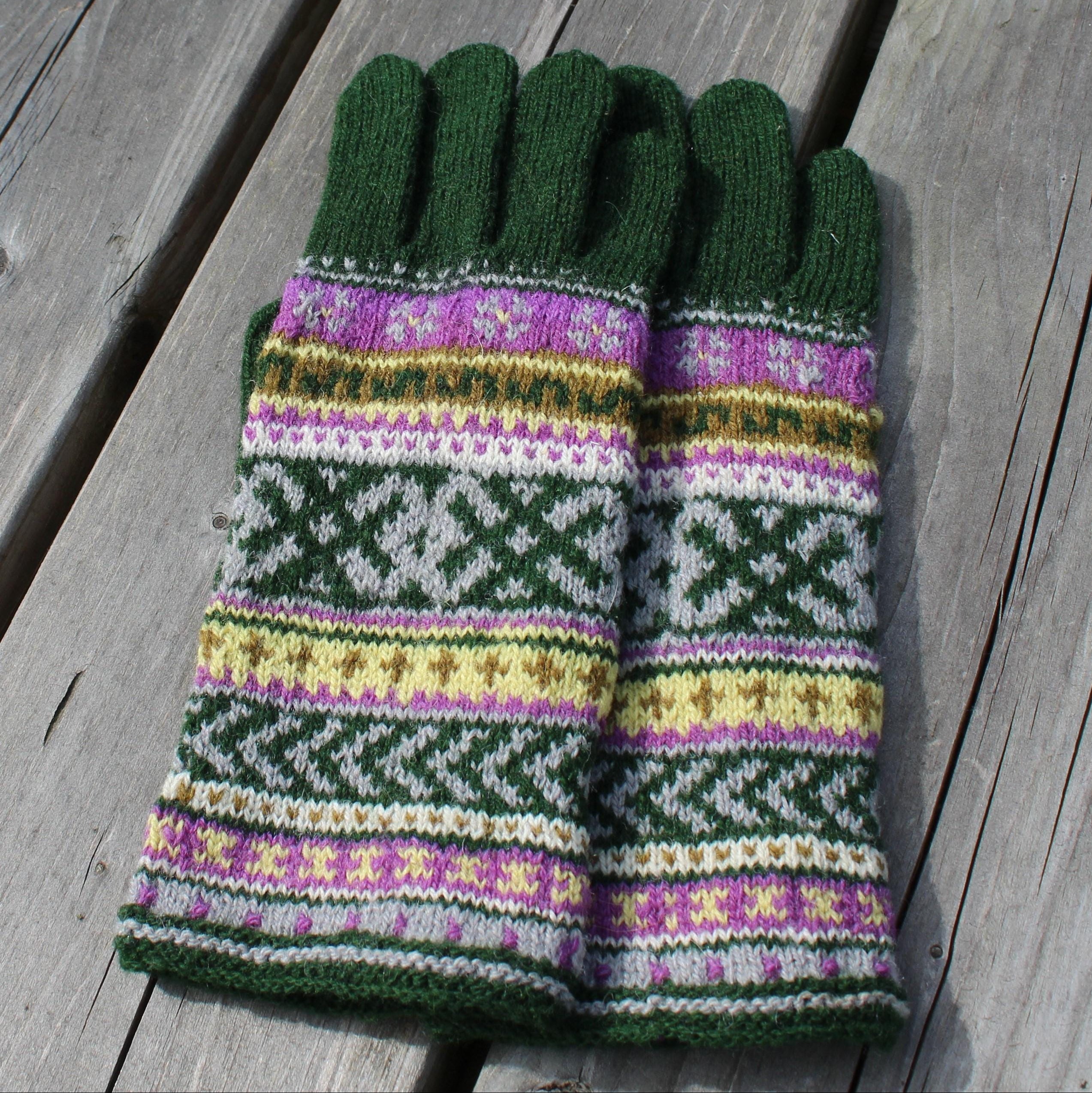 Pair of green gloves with a colorful pattern on a wooden surface