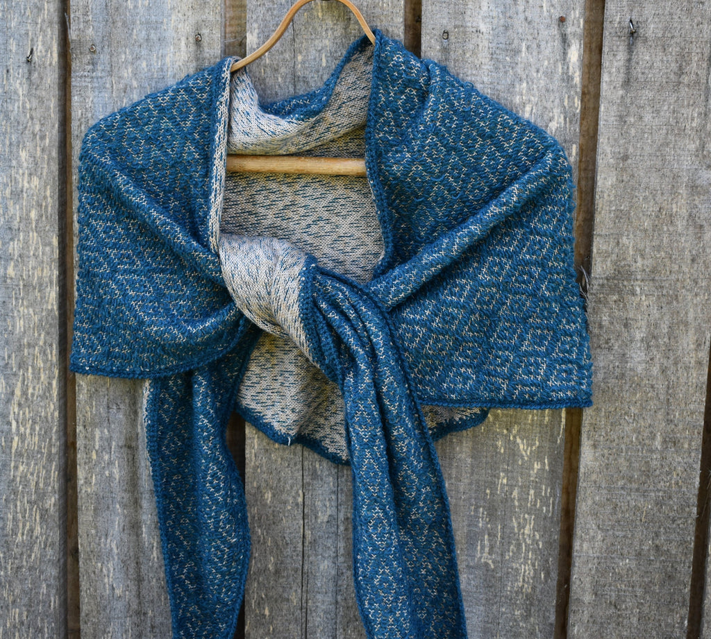 Blue knitted scarf draped over a wooden hanger against a wooden background