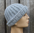 Knitted gray beanie on a mannequin head against a wooden background