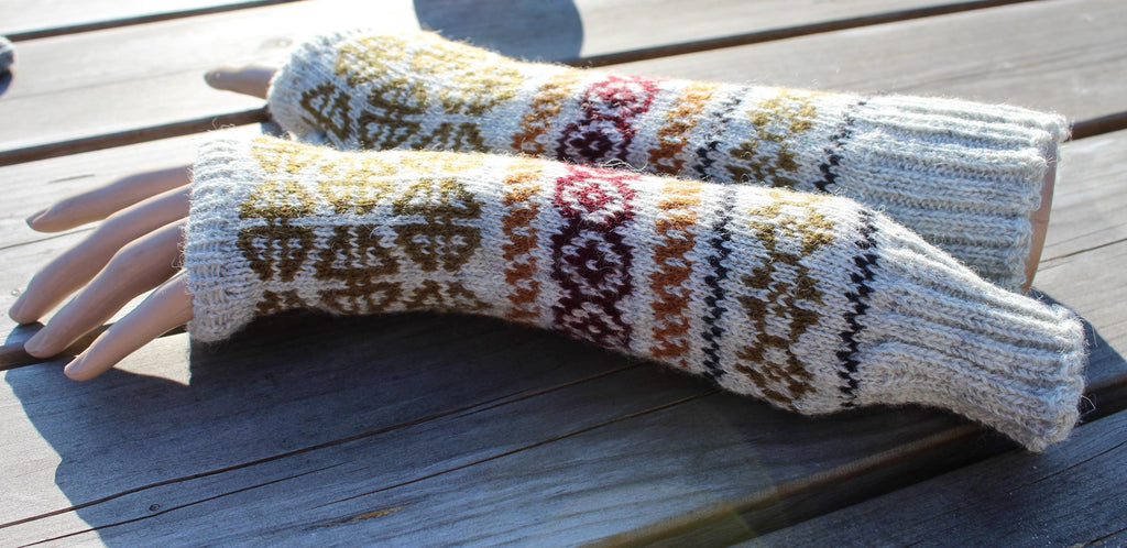 Pair of patterned knitted arm warmers on a wooden surface