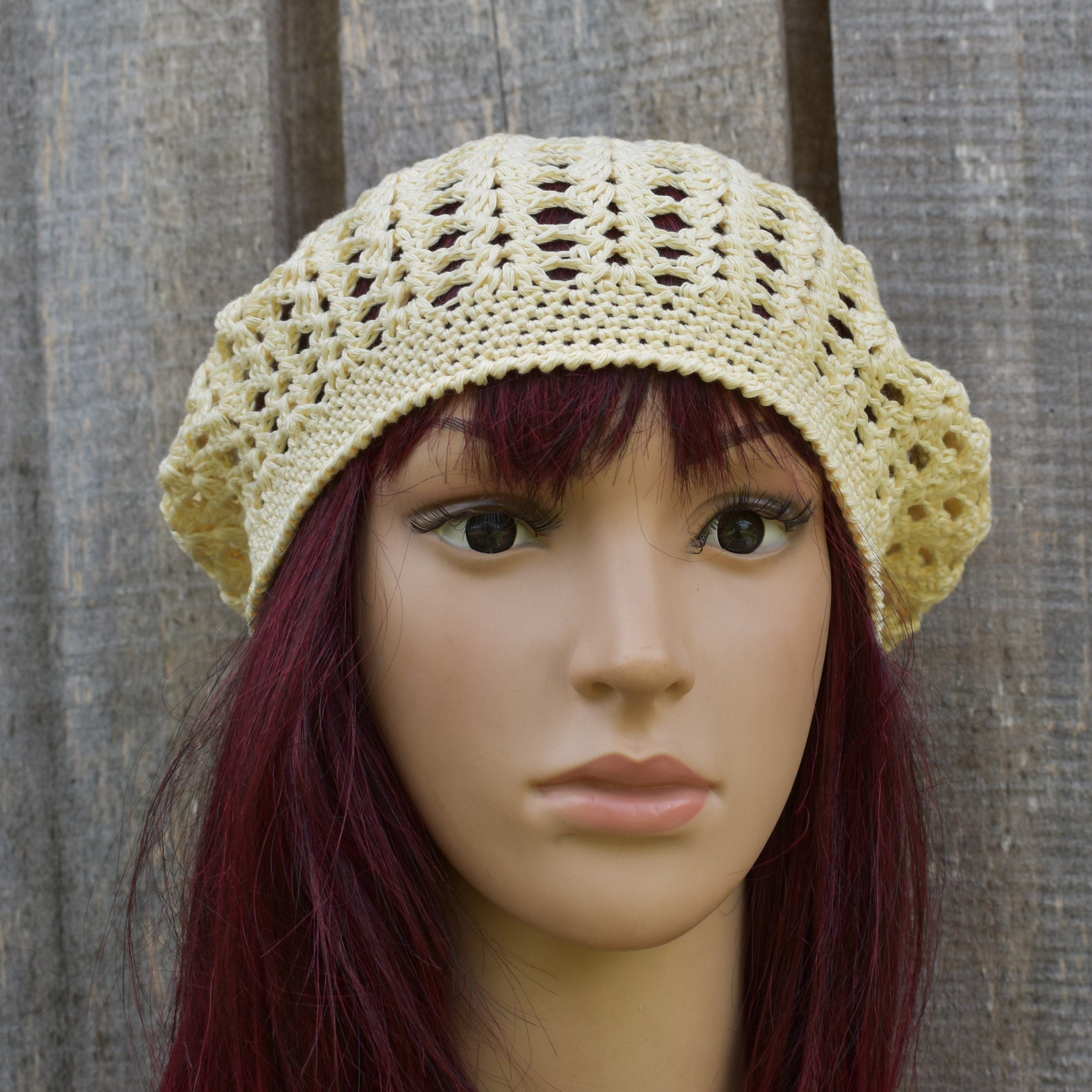 Beige crochet hat on a mannequin head against a wooden background