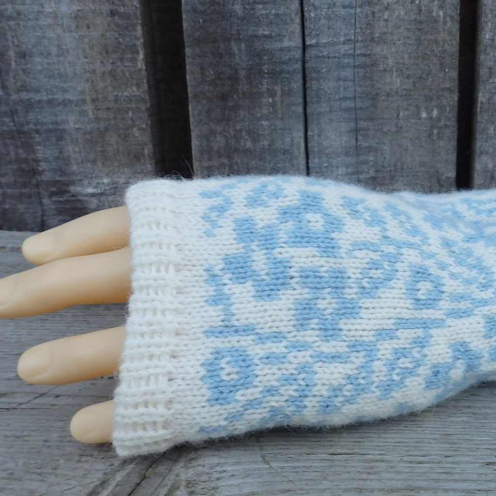 Knitted wrist warmer with blue pattern on a wooden surface