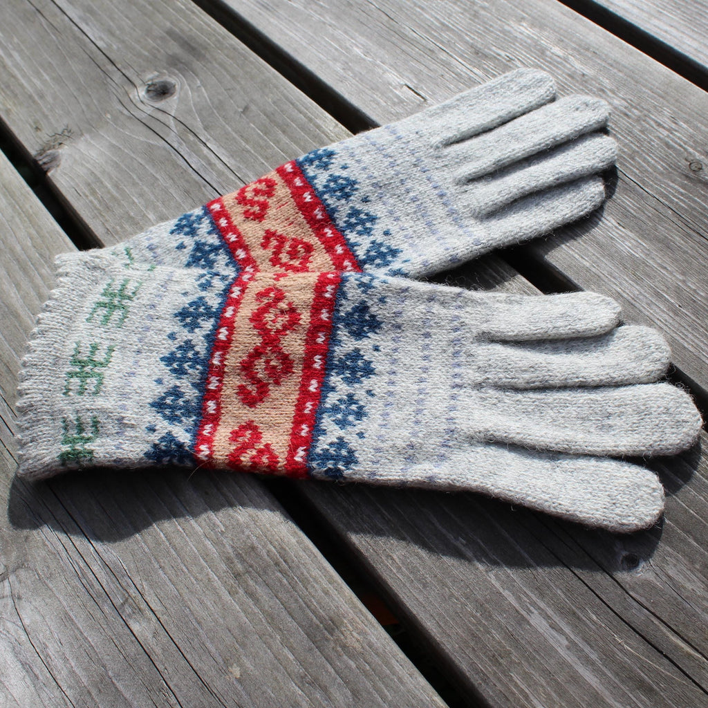 Pair of gray gloves with colorful pattern on a wooden surface