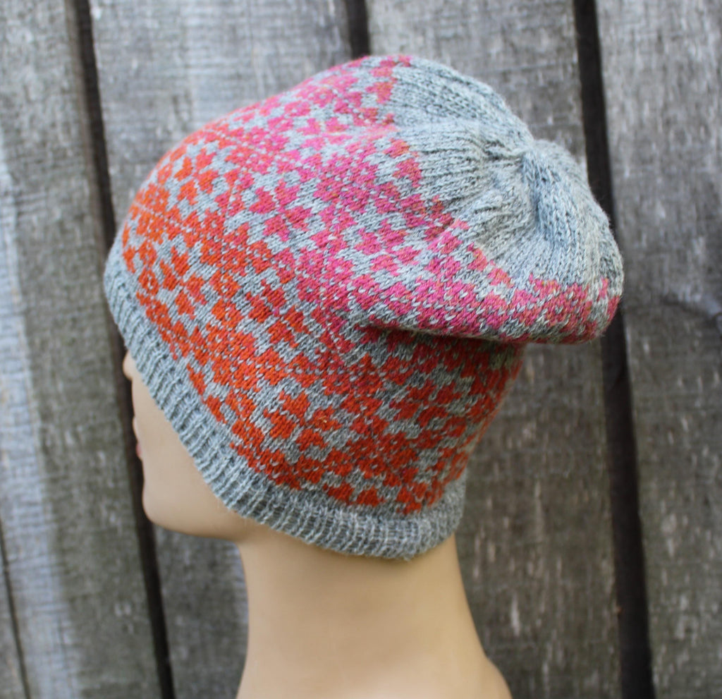 Knitted hat with a geometric pattern on a mannequin head against a wooden background