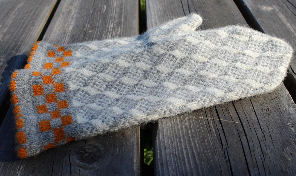 Gray and orange knitted glove on a wooden surface