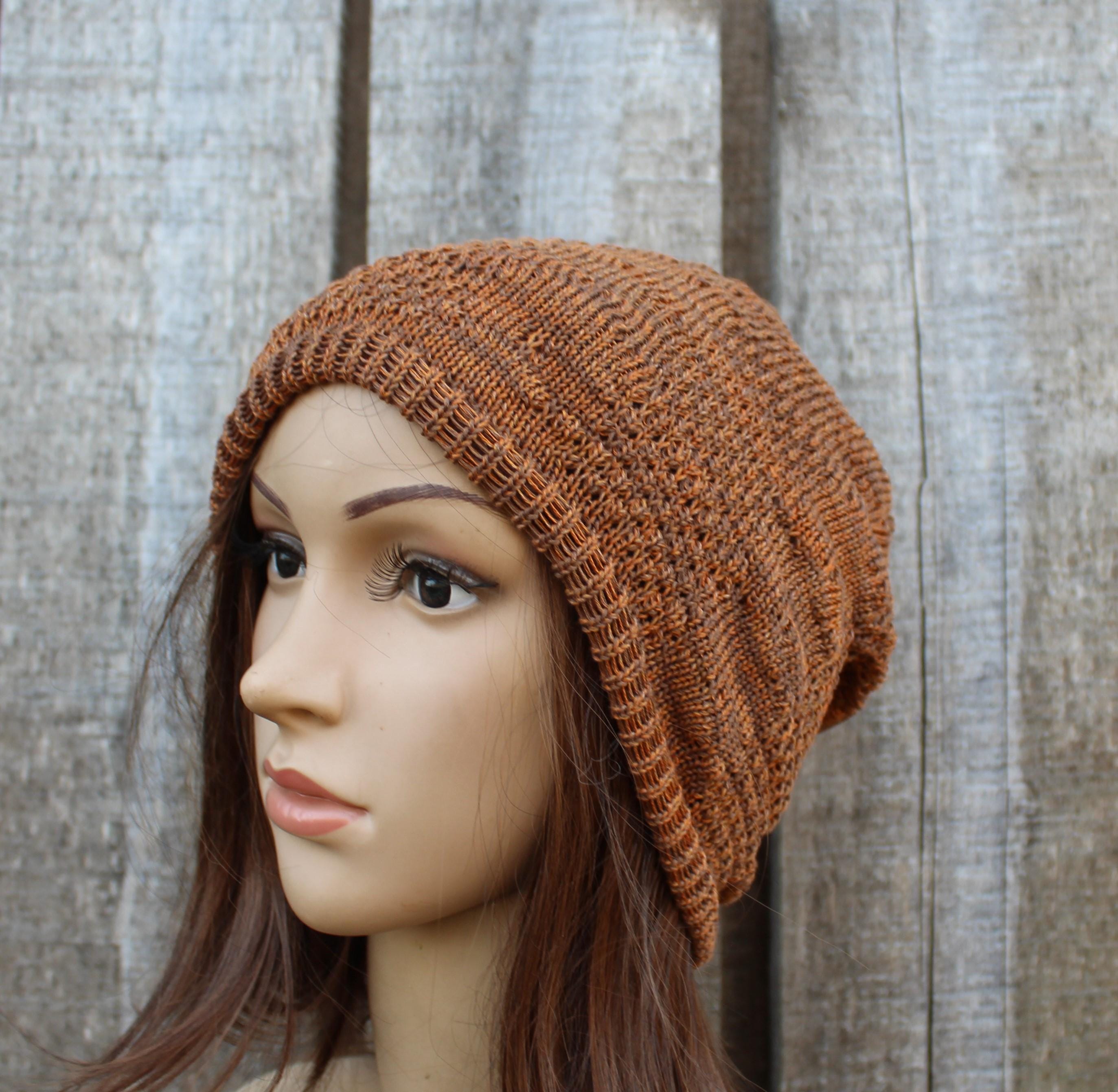 Mannequin head wearing a brown knitted beanie against a wooden background