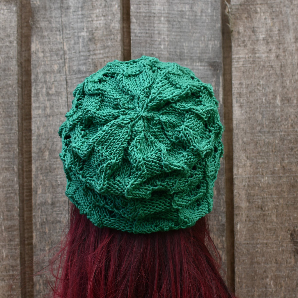 Green knitted hat on a person with red hair against a wooden background