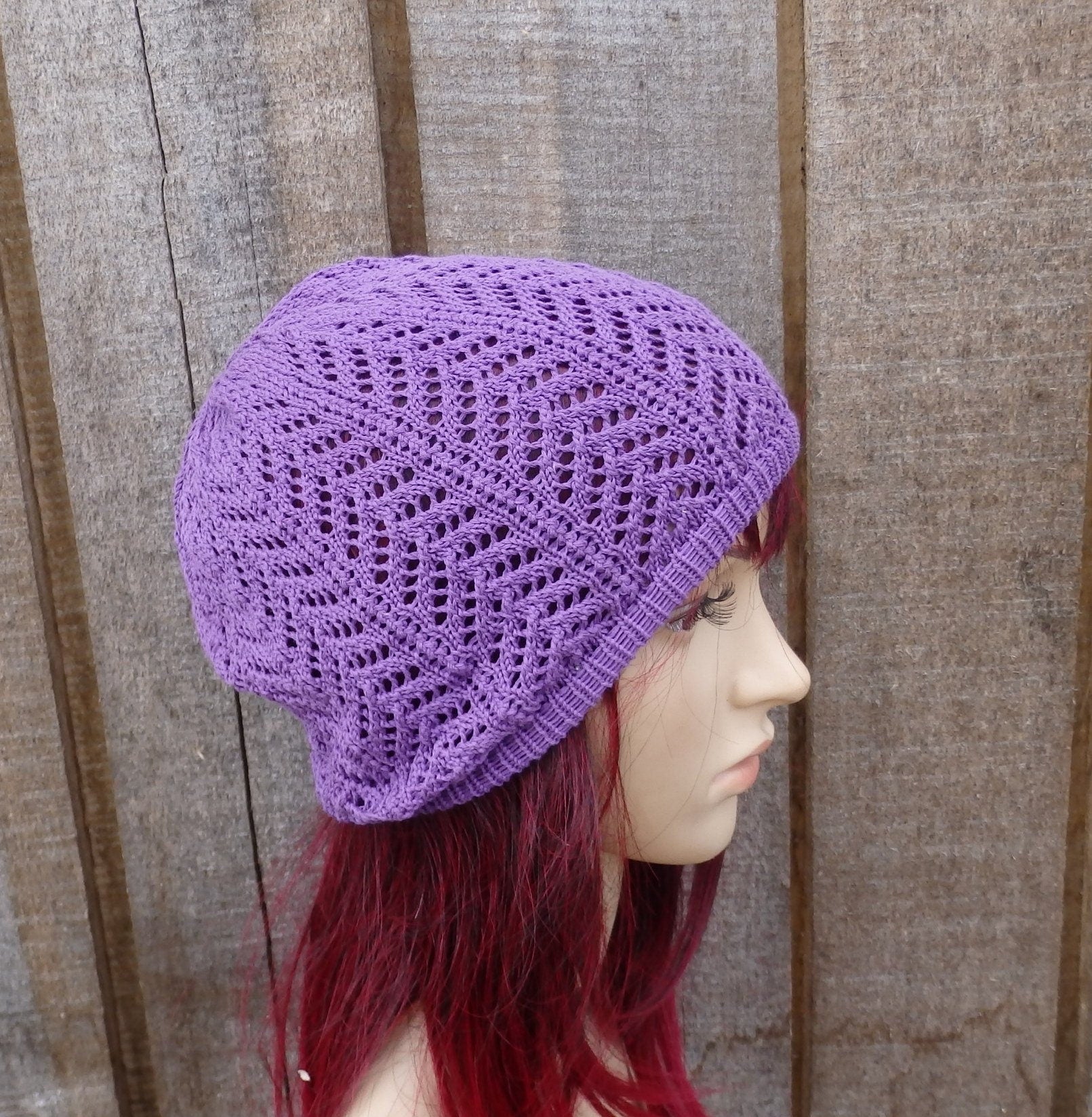 Purple knitted hat worn by a mannequin against a wooden background