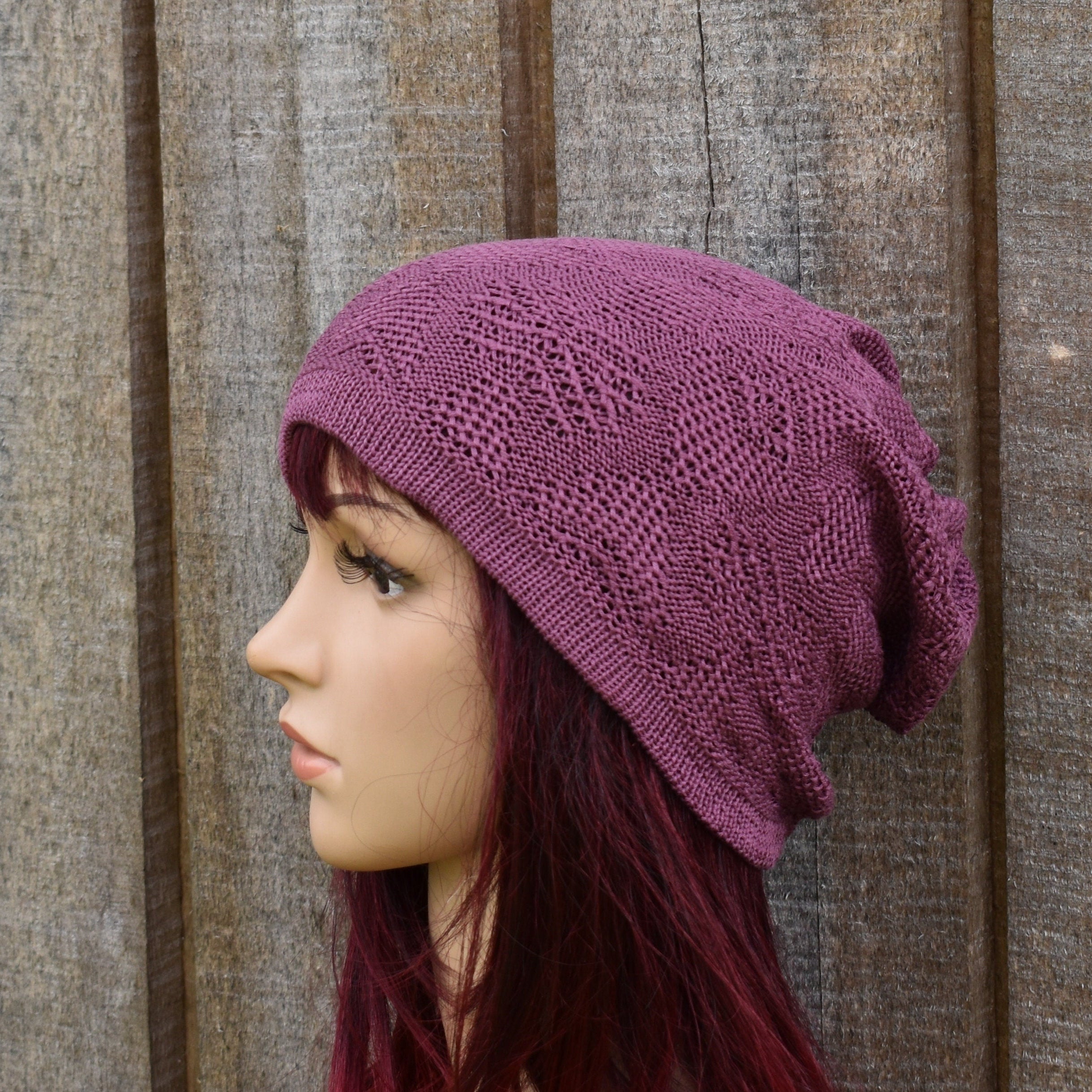 Purple knitted beanie on a mannequin head against a wooden background