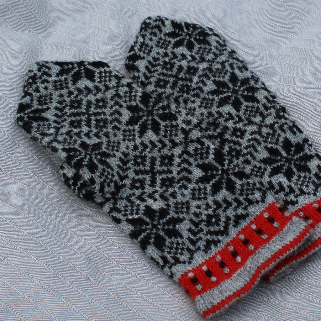 Knitted mitten with black and white pattern on a light gray background
