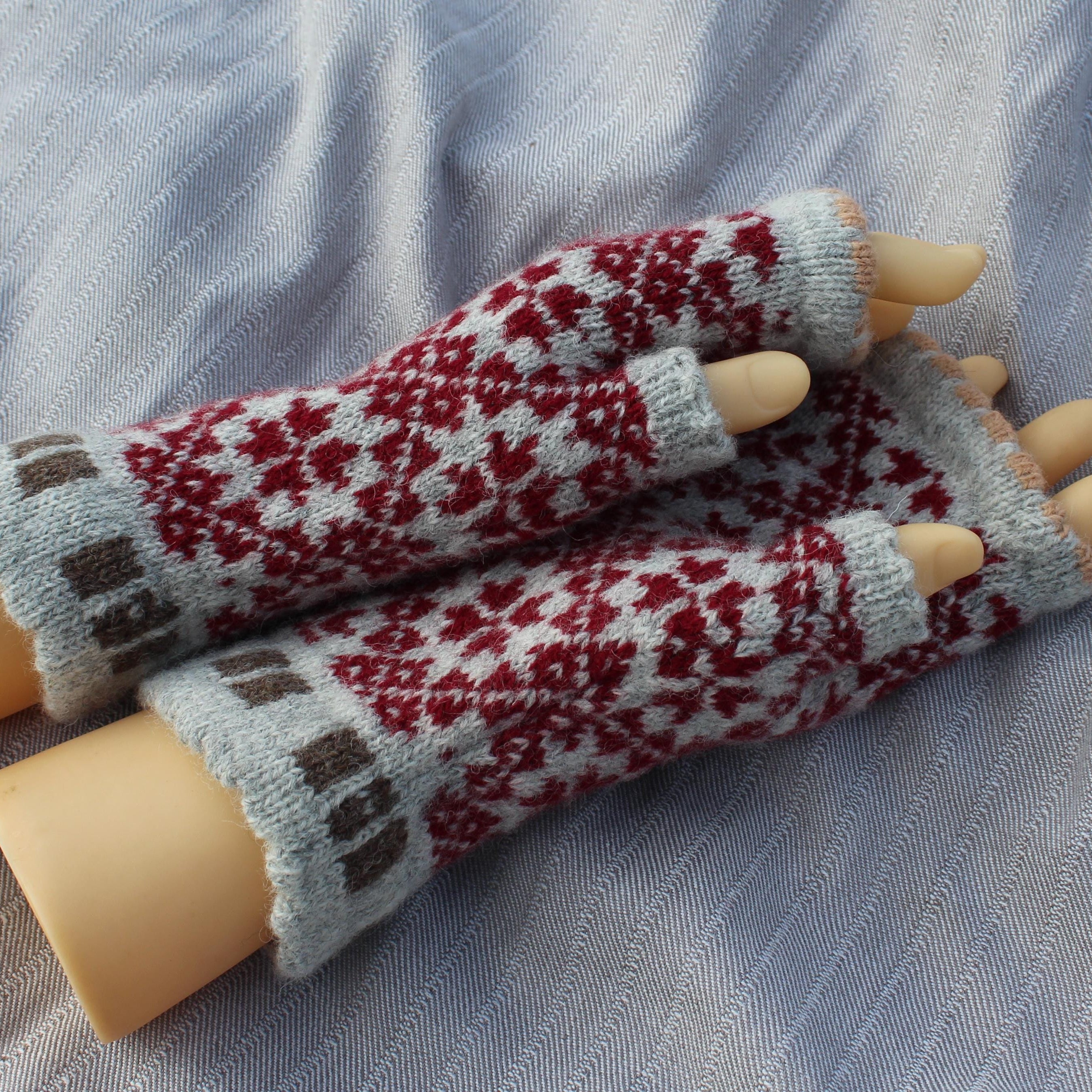 Pair of knitted fingerless gloves with a pattern on a textured fabric background