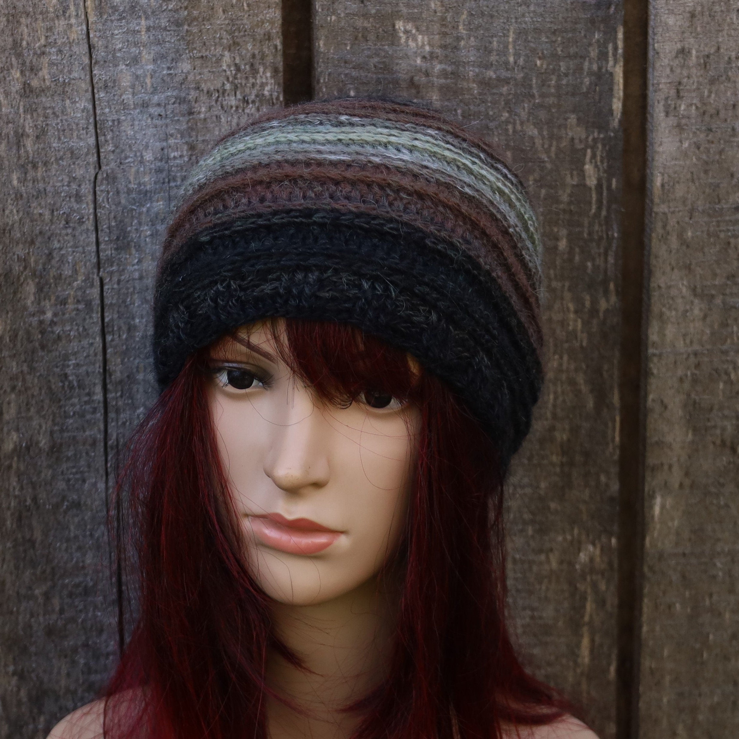 Mannequin head wearing a multicolored knit beanie against a wooden background