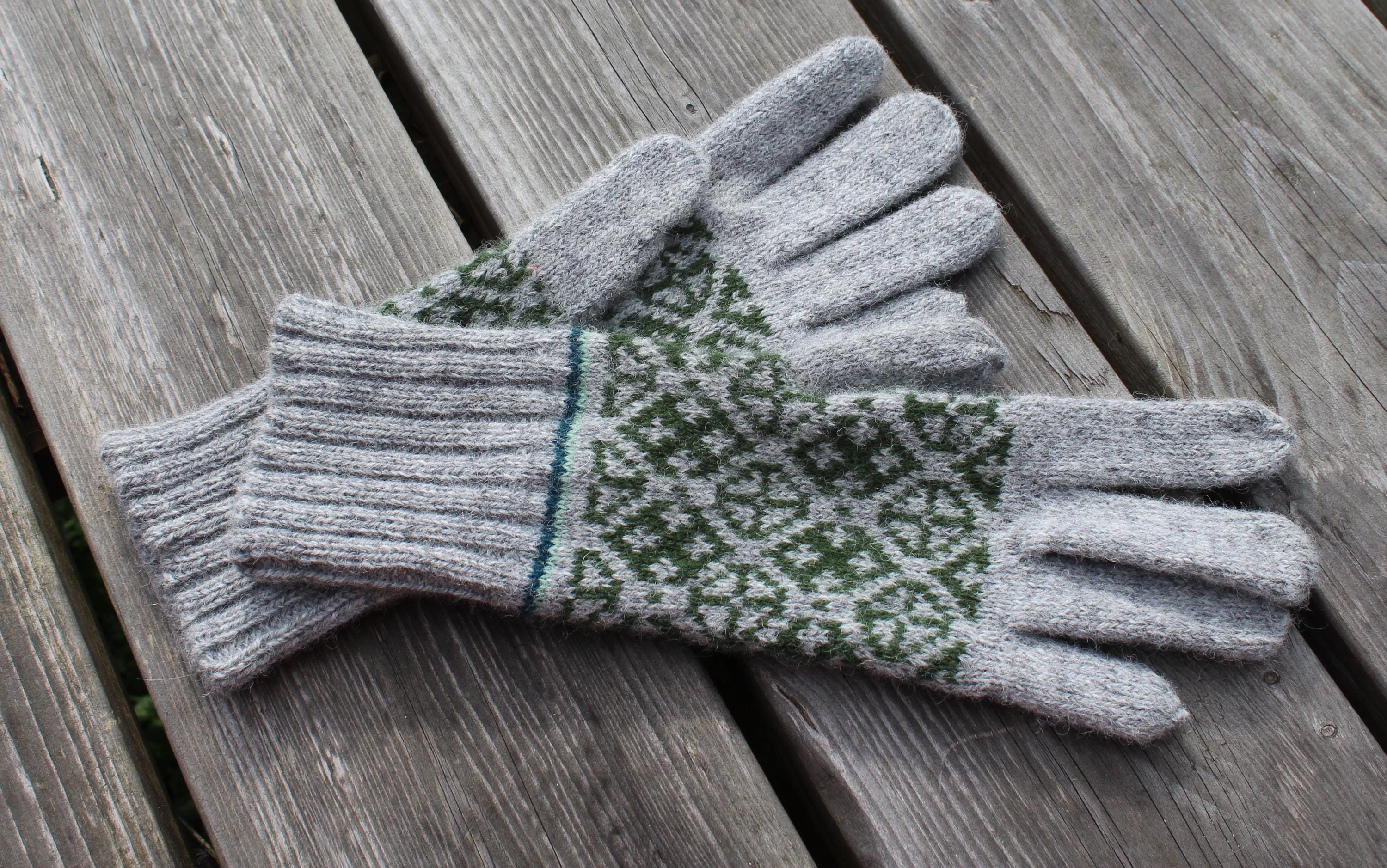 Pair of gray and green gloves on a wooden surface