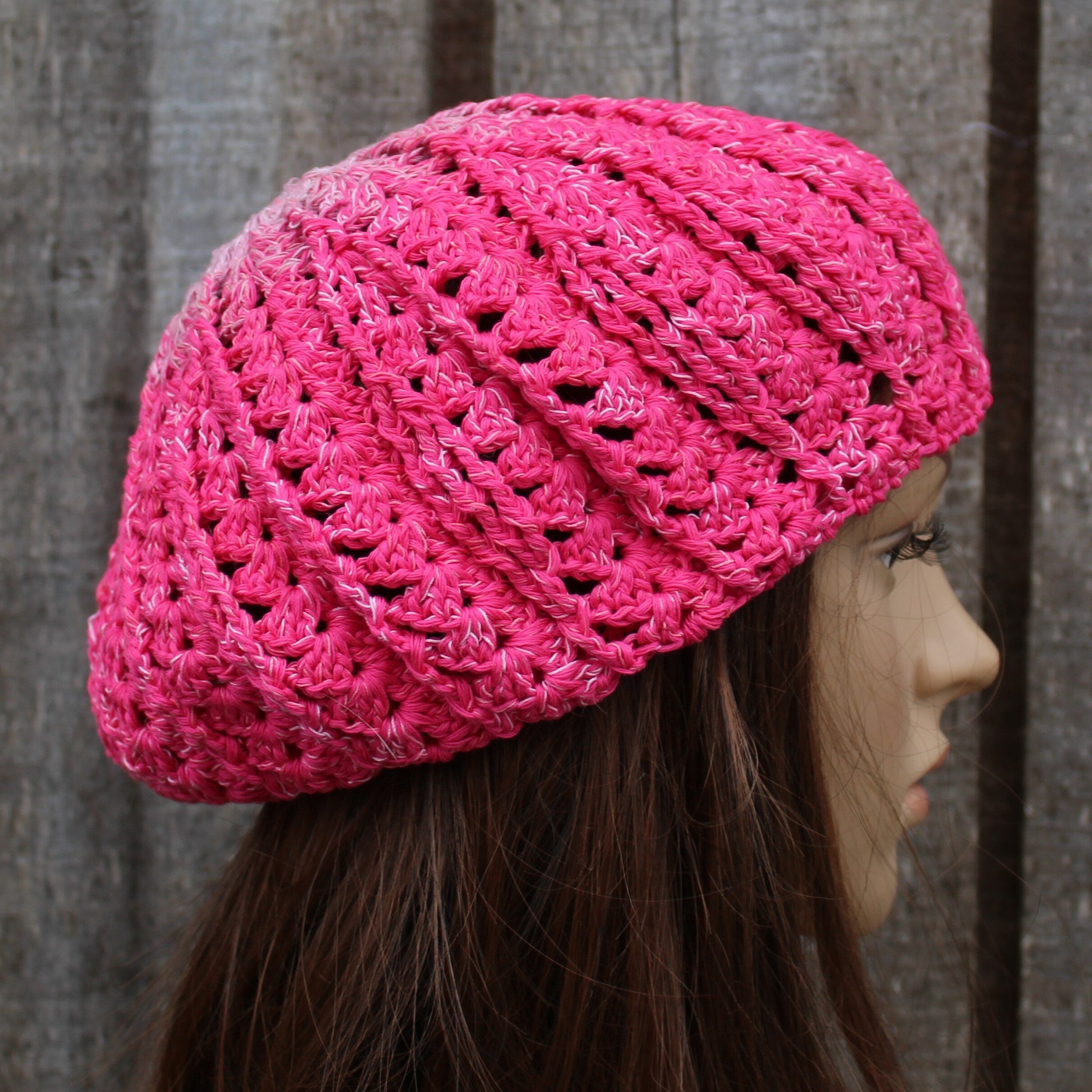 Pink knitted hat on a mannequin head against a wooden background