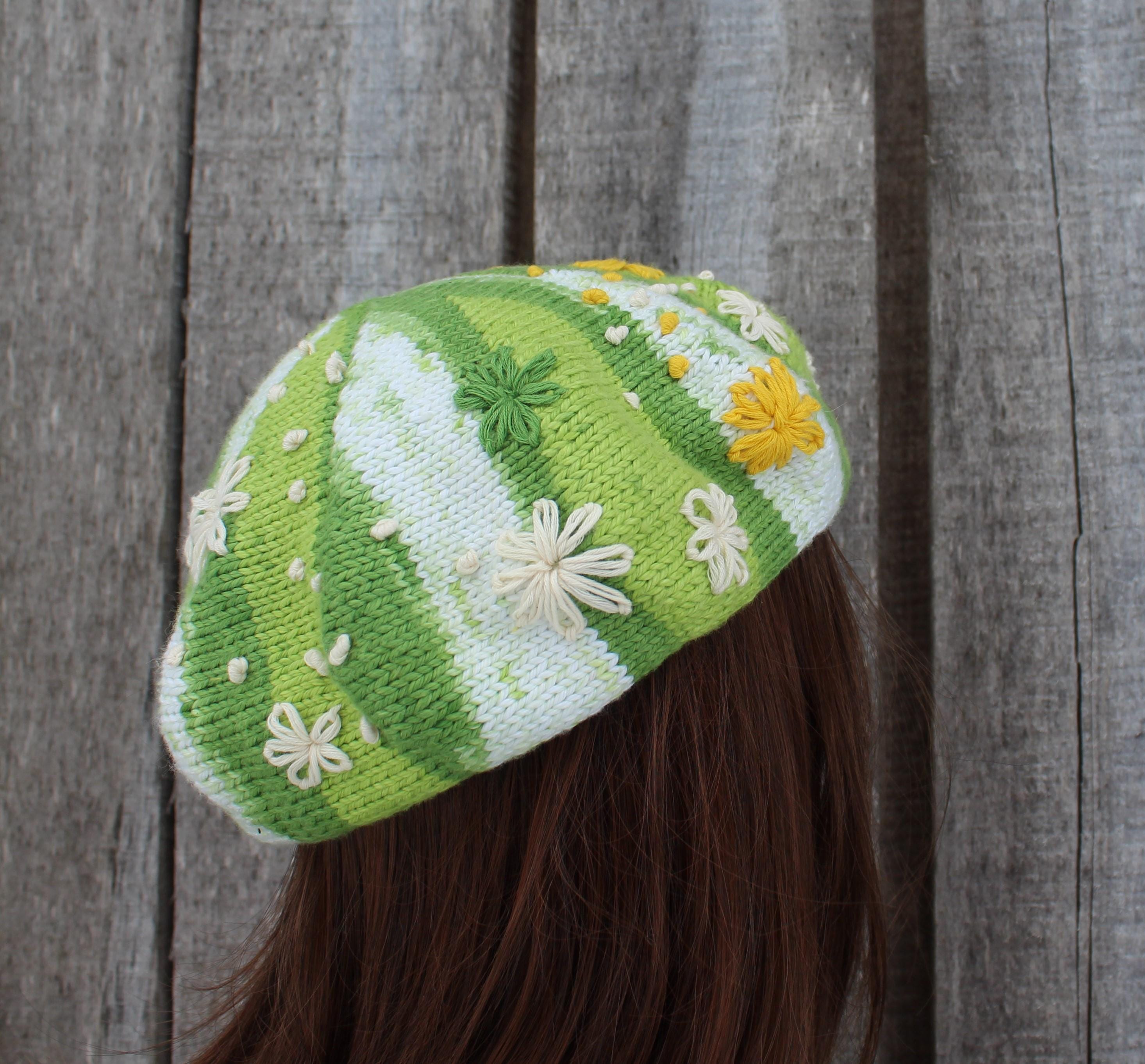Green and white striped knit hat with floral patterns against a wooden background
