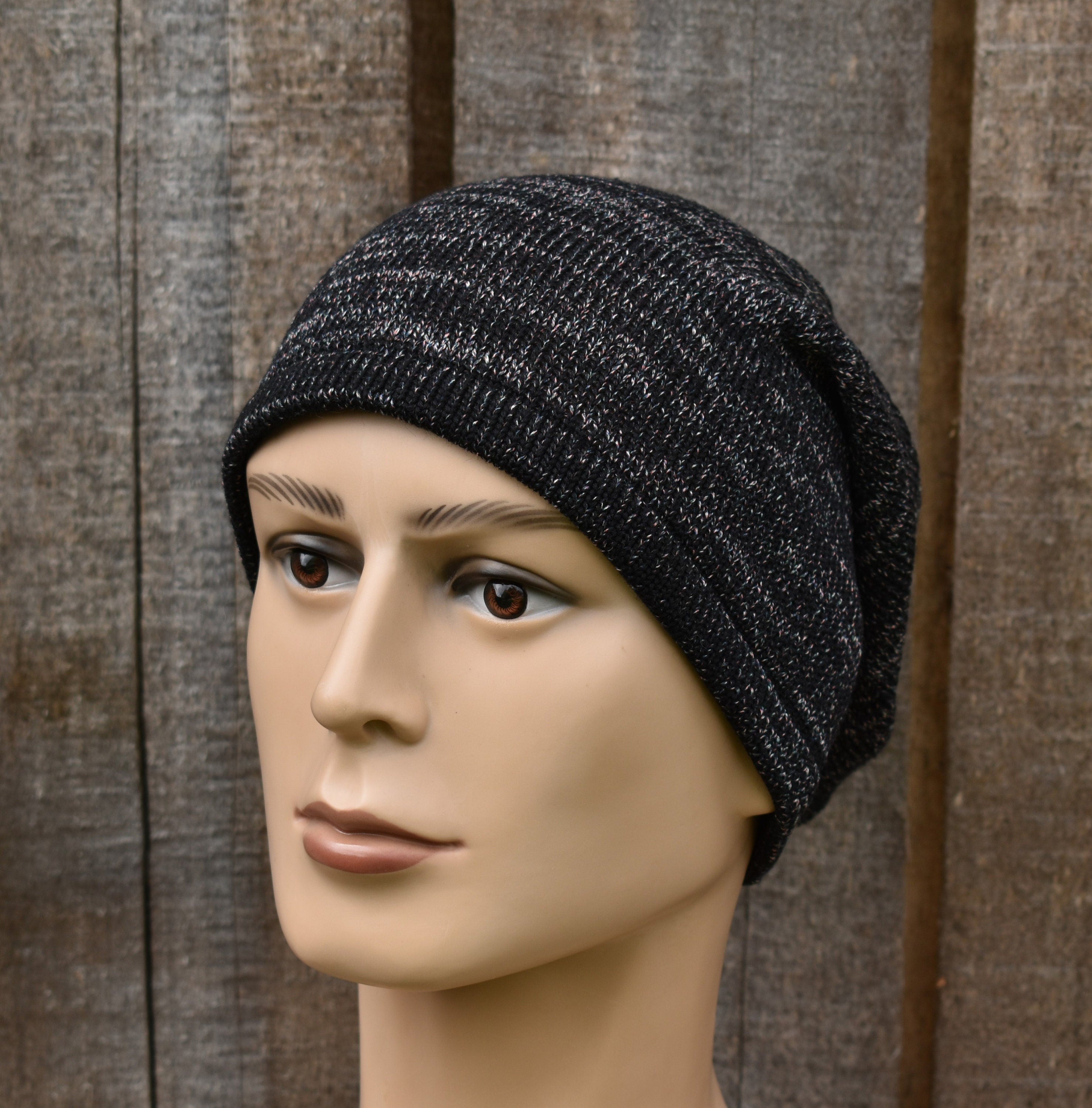 Mannequin head wearing a black knit beanie against a wooden background