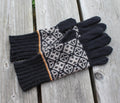 Pair of black gloves with a patterned palm on a wooden surface