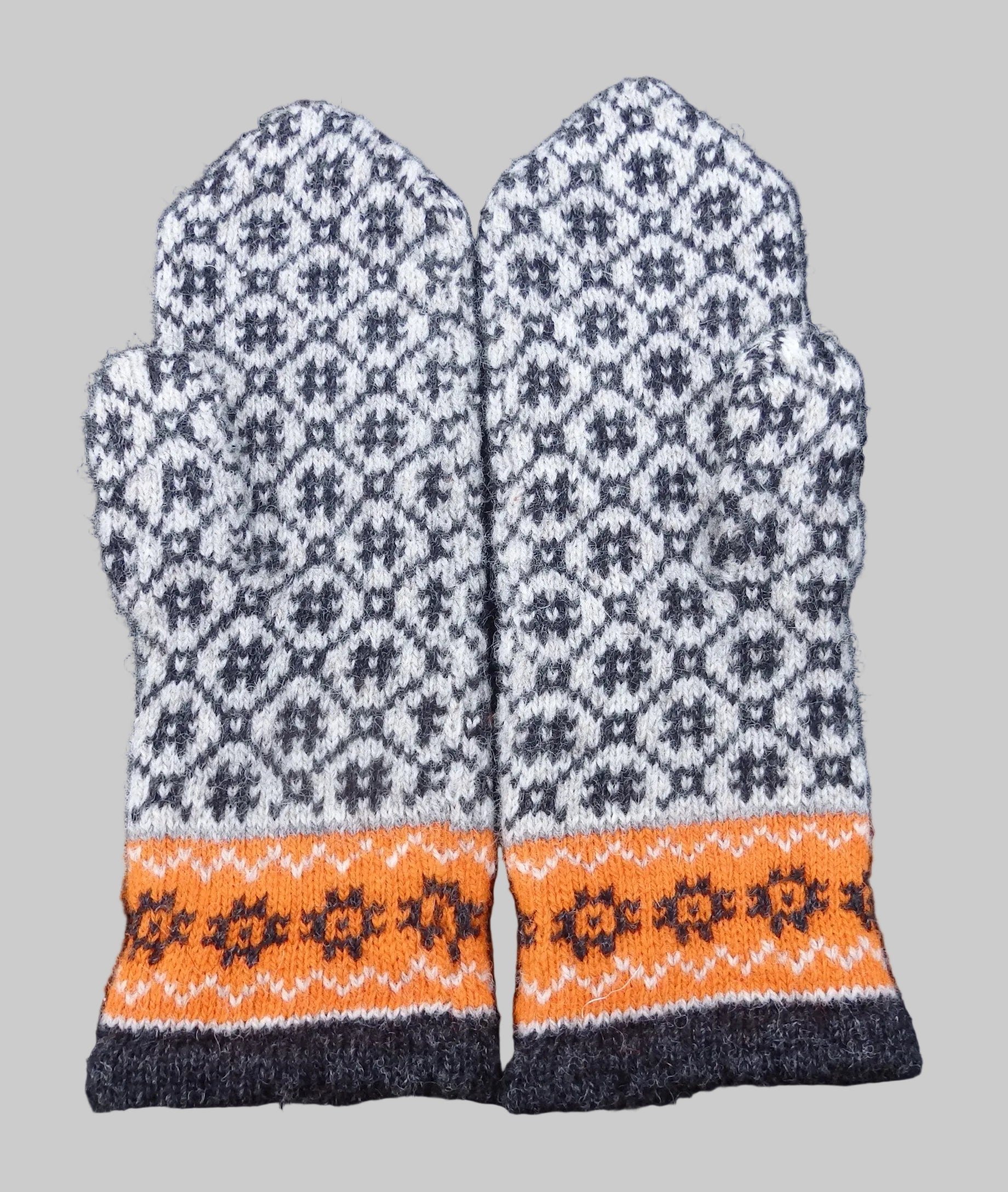 Pair of knitted mittens with a geometric pattern on a dark background