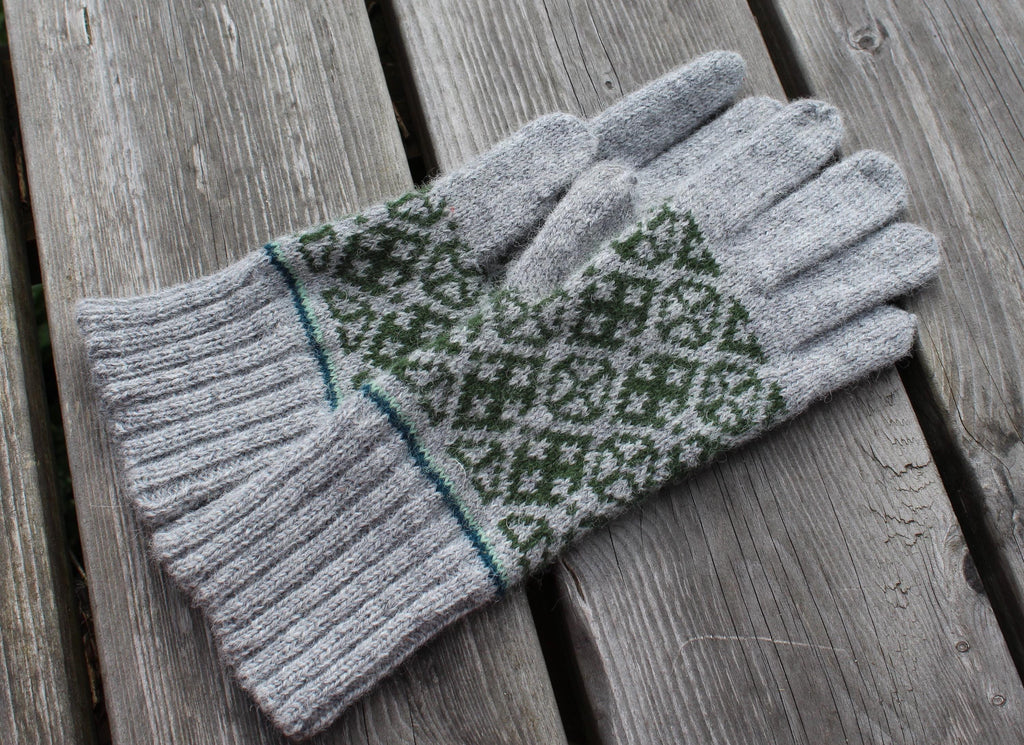 Pair of gray gloves with green pattern on a wooden surface