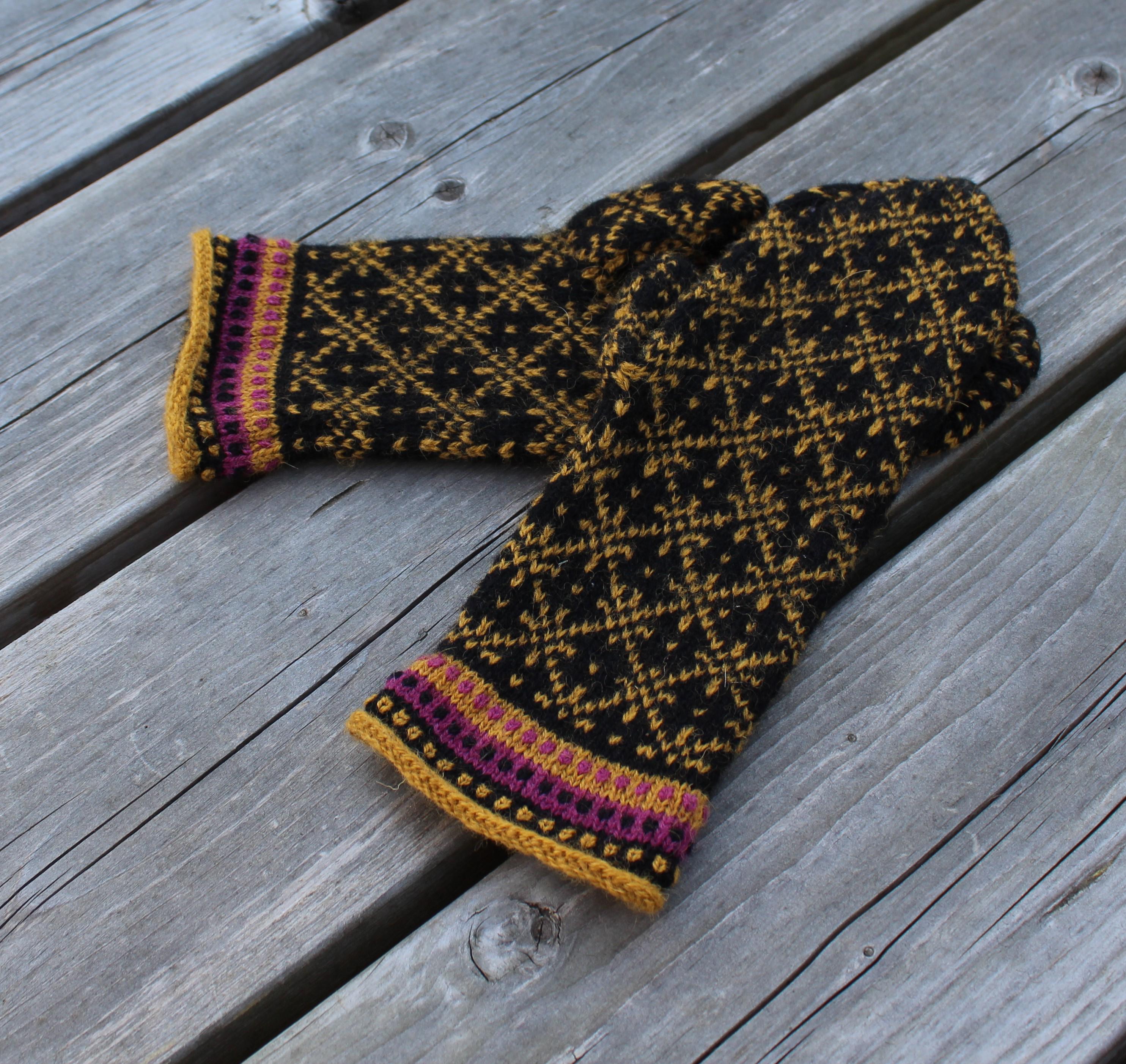 Pair of black and yellow patterned mittens on a wooden surface