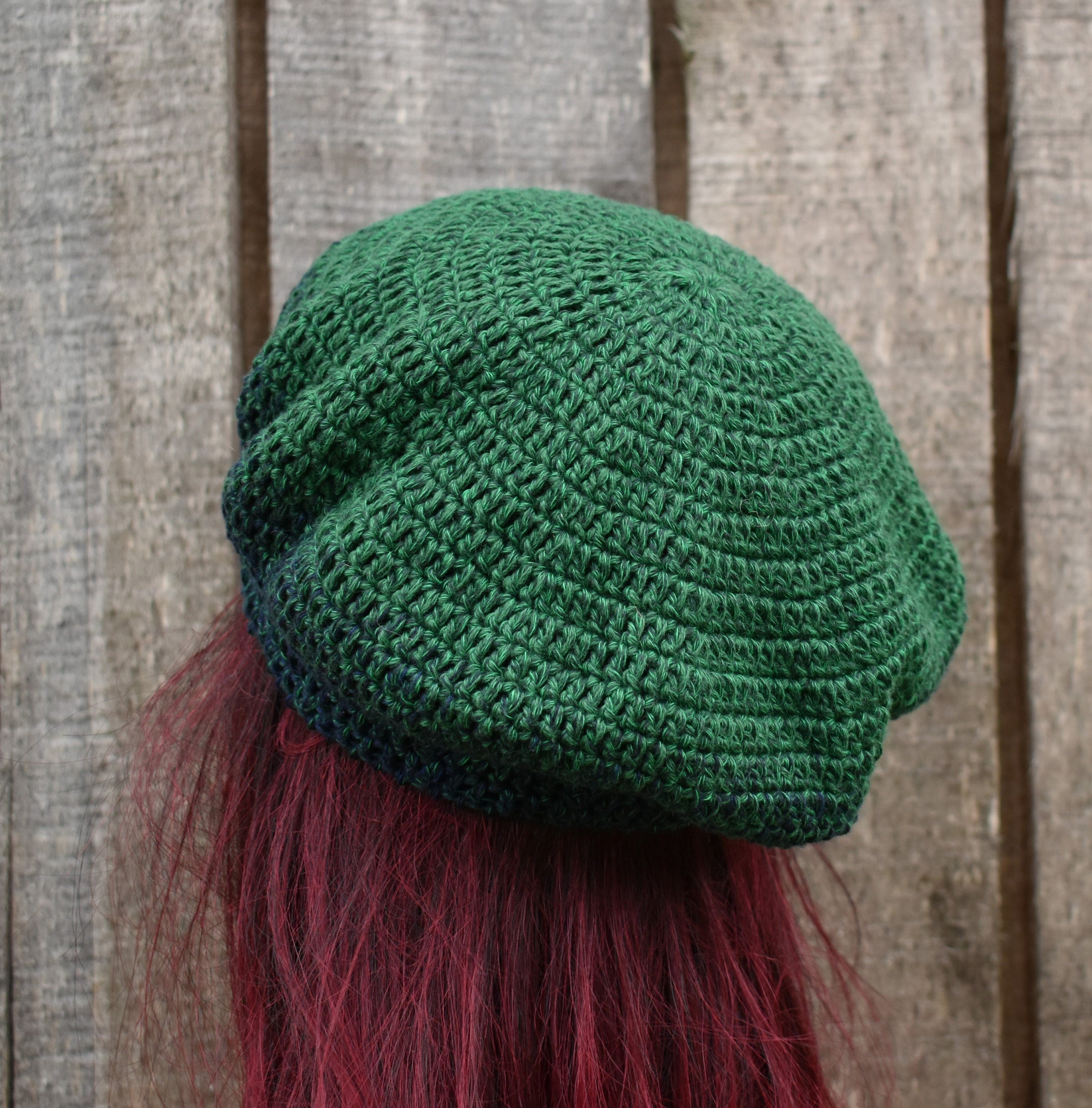 Green knitted beanie with red hair on a wooden background