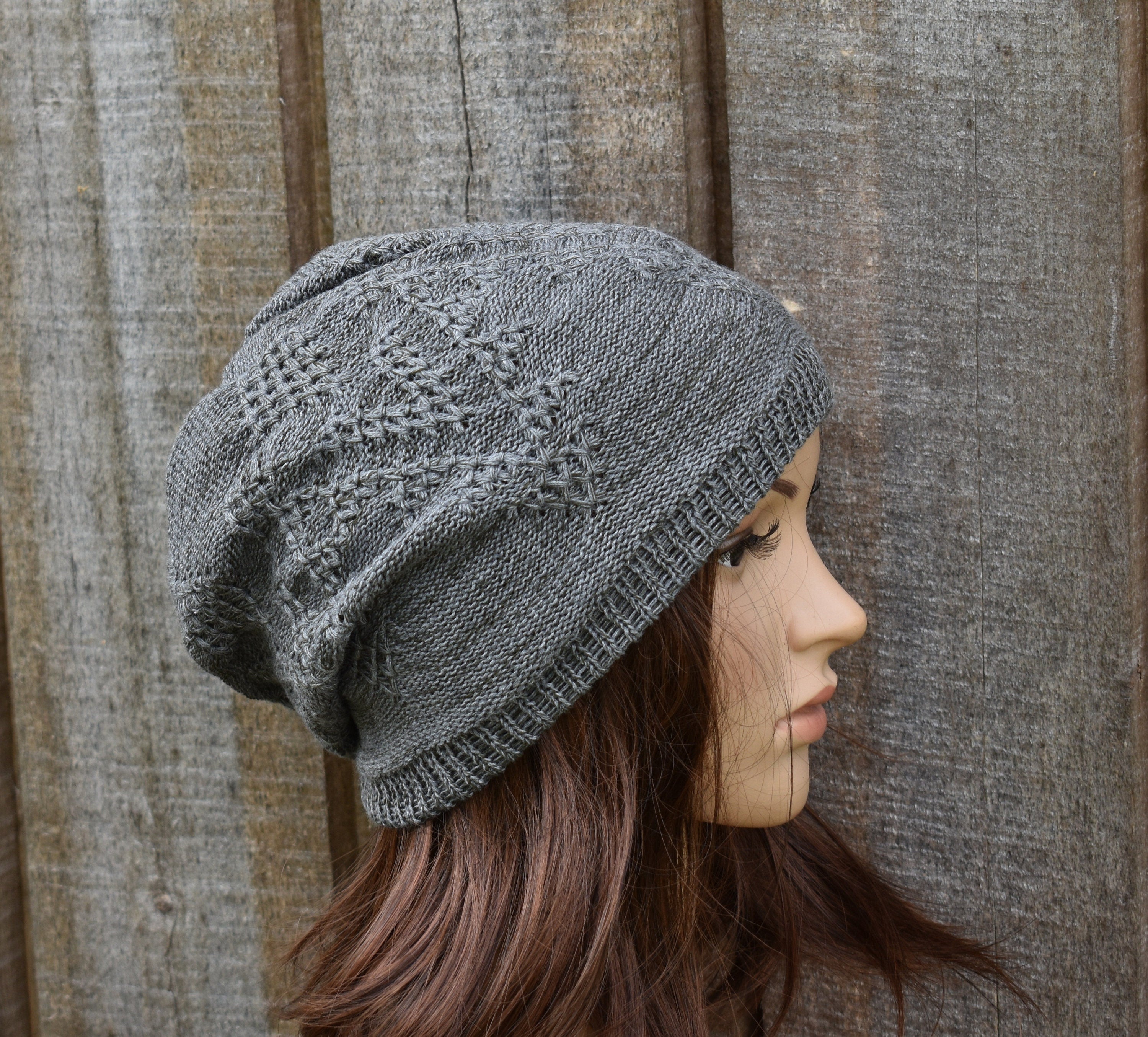 Woman wearing a gray knit beanie against a wooden background
