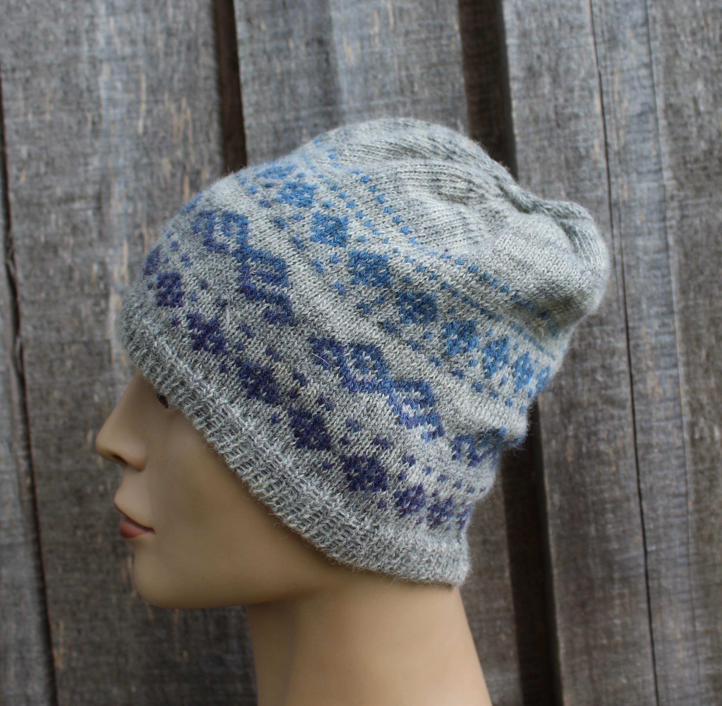 Gray knit hat with blue pattern on a mannequin head against a wooden background