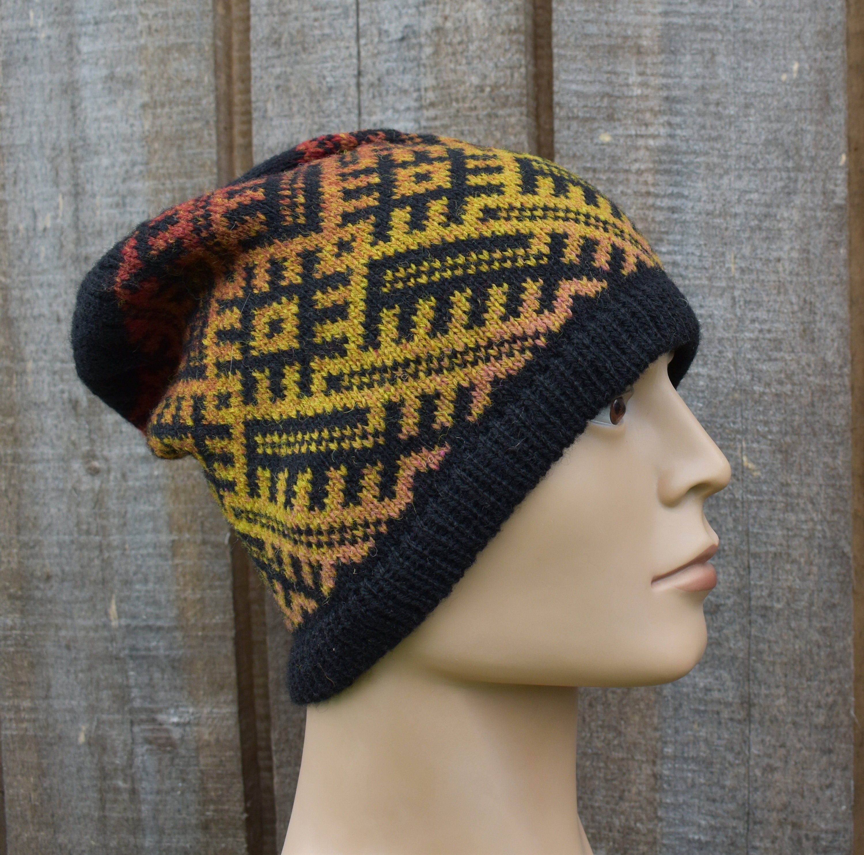 Knitted beanie with geometric pattern on a mannequin head against a wooden background
