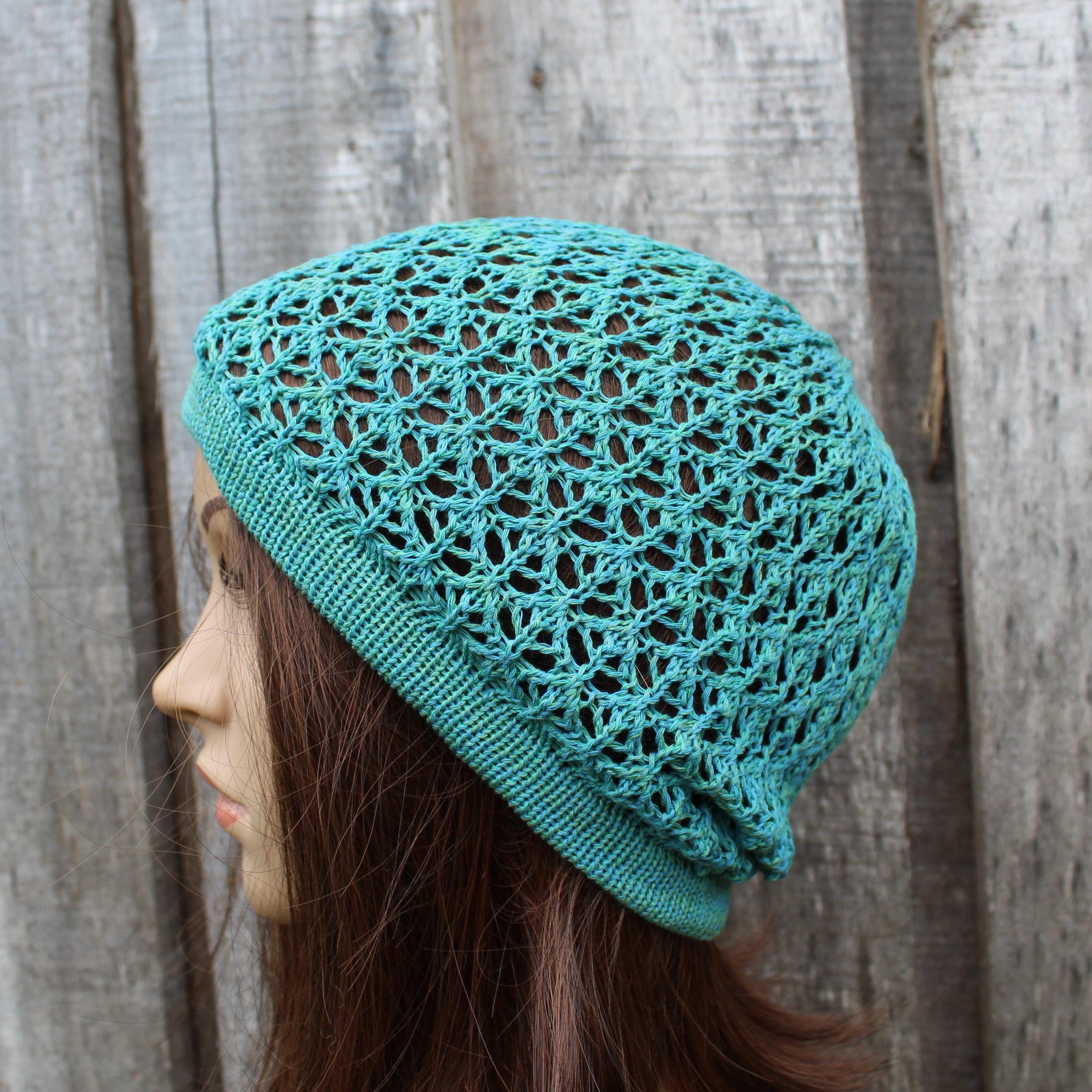 Turquoise knitted hat worn by a person against a wooden background