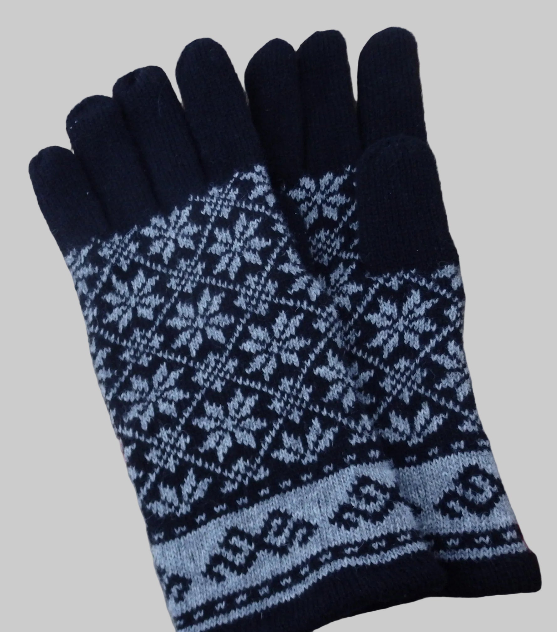 Pair of black and blue patterned gloves on a textured surface