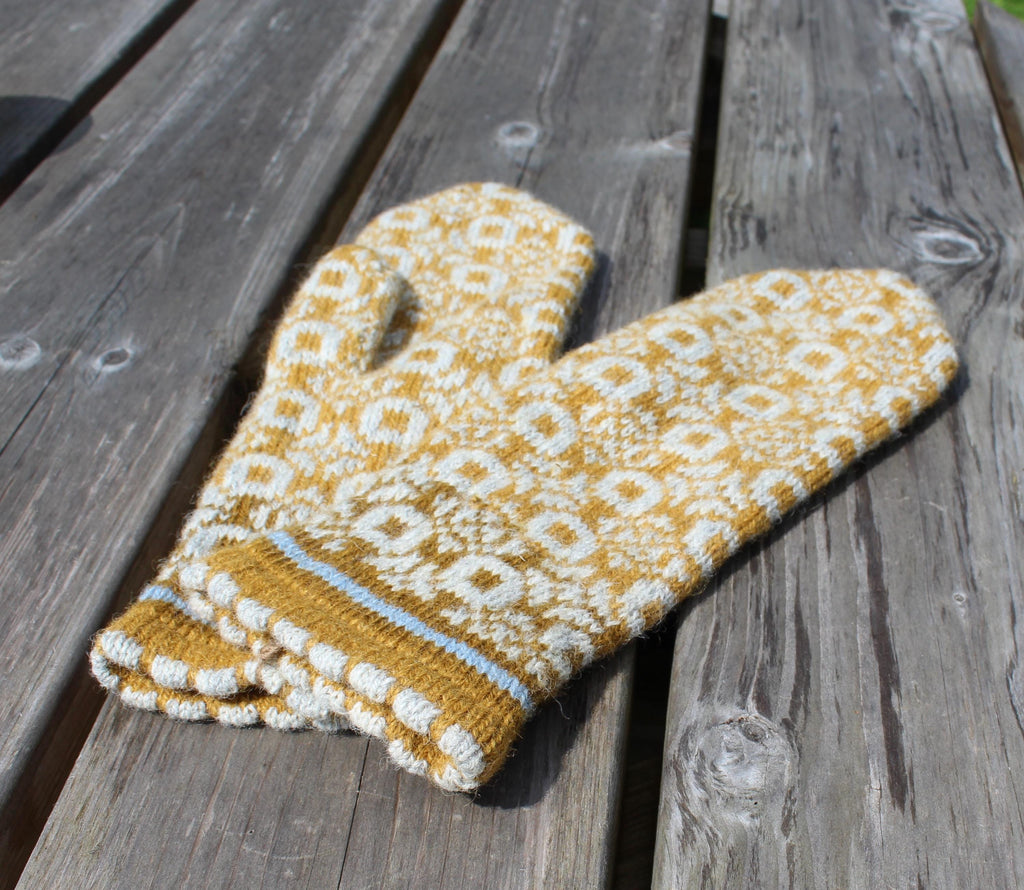 Knitted yellow and white patterned glove on a wooden surface