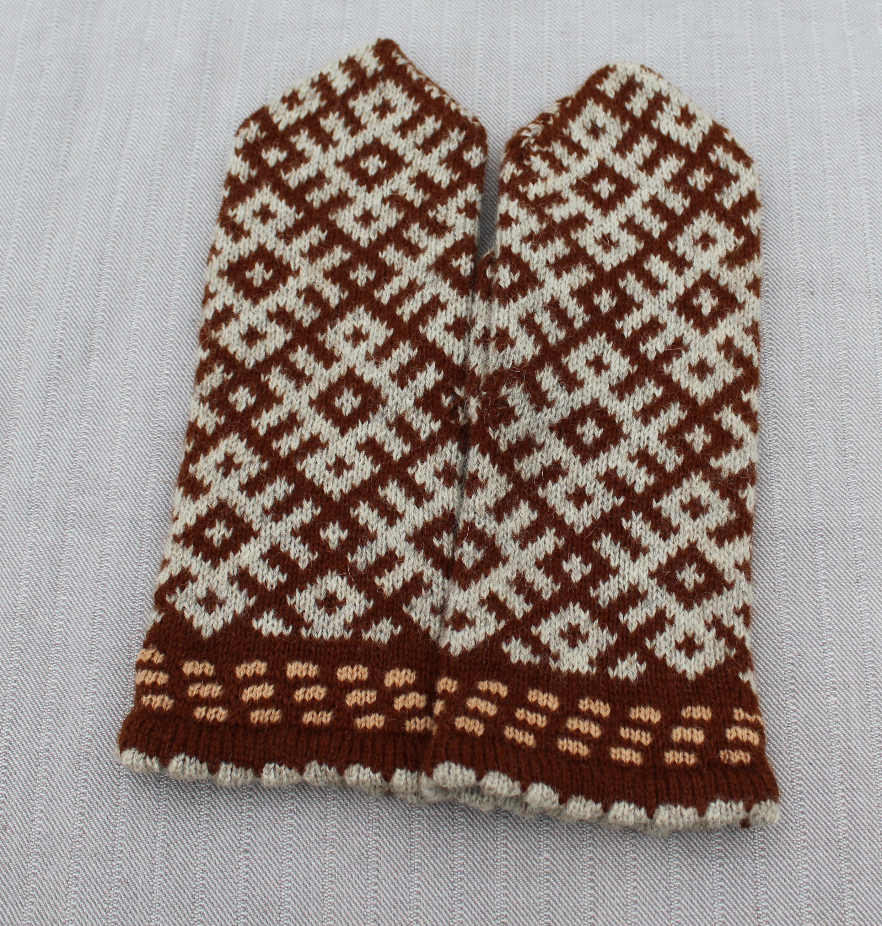 Pair of knitted mittens with a brown and white pattern on a light gray background