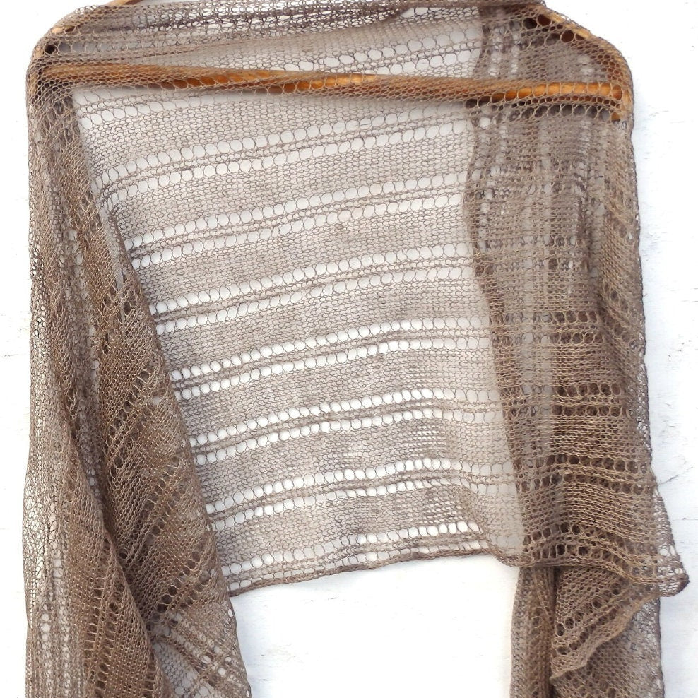 Brown knitted shawl on a wooden hanger against a white background