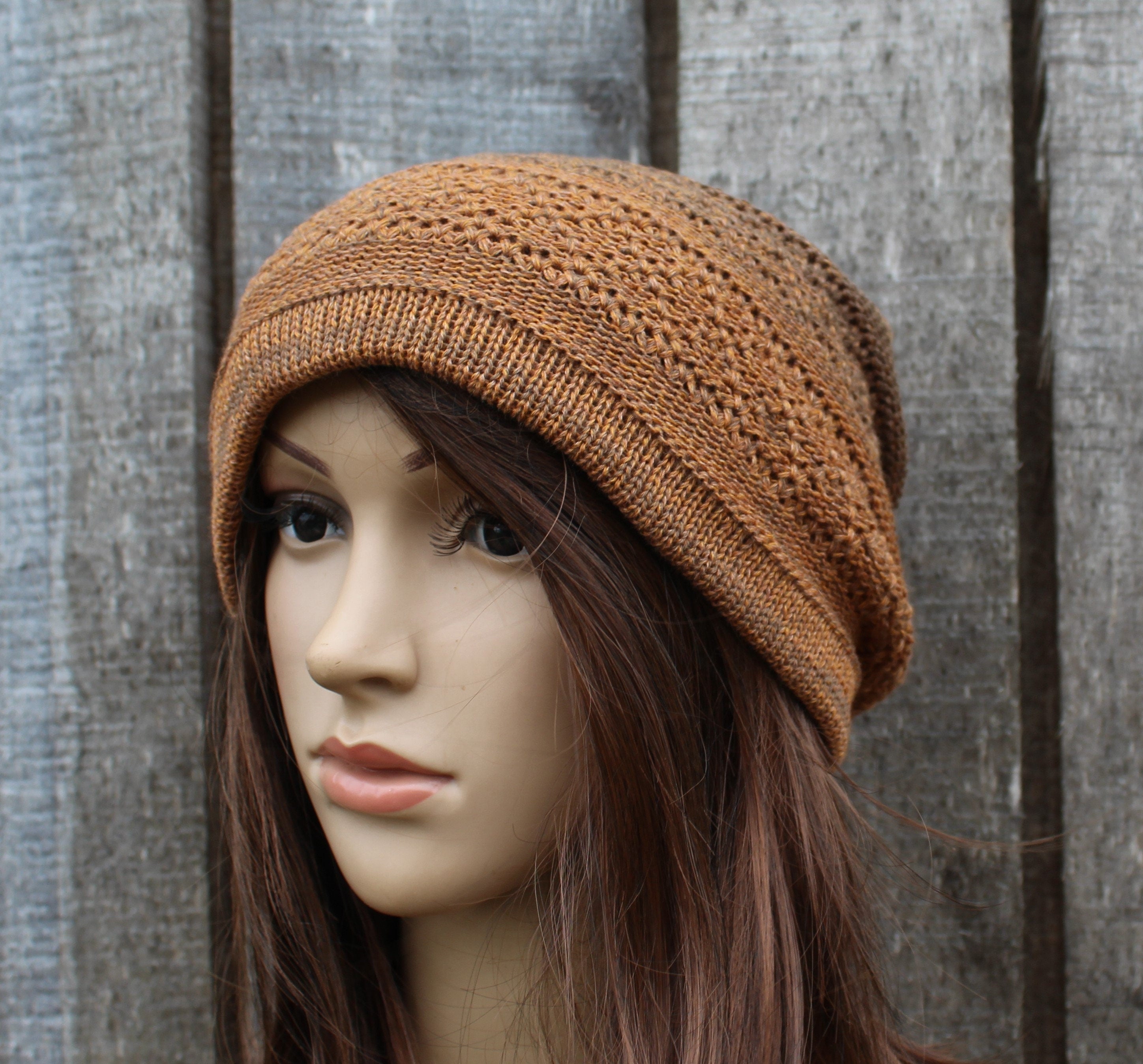 Brown knitted beanie on a mannequin head against a wooden background