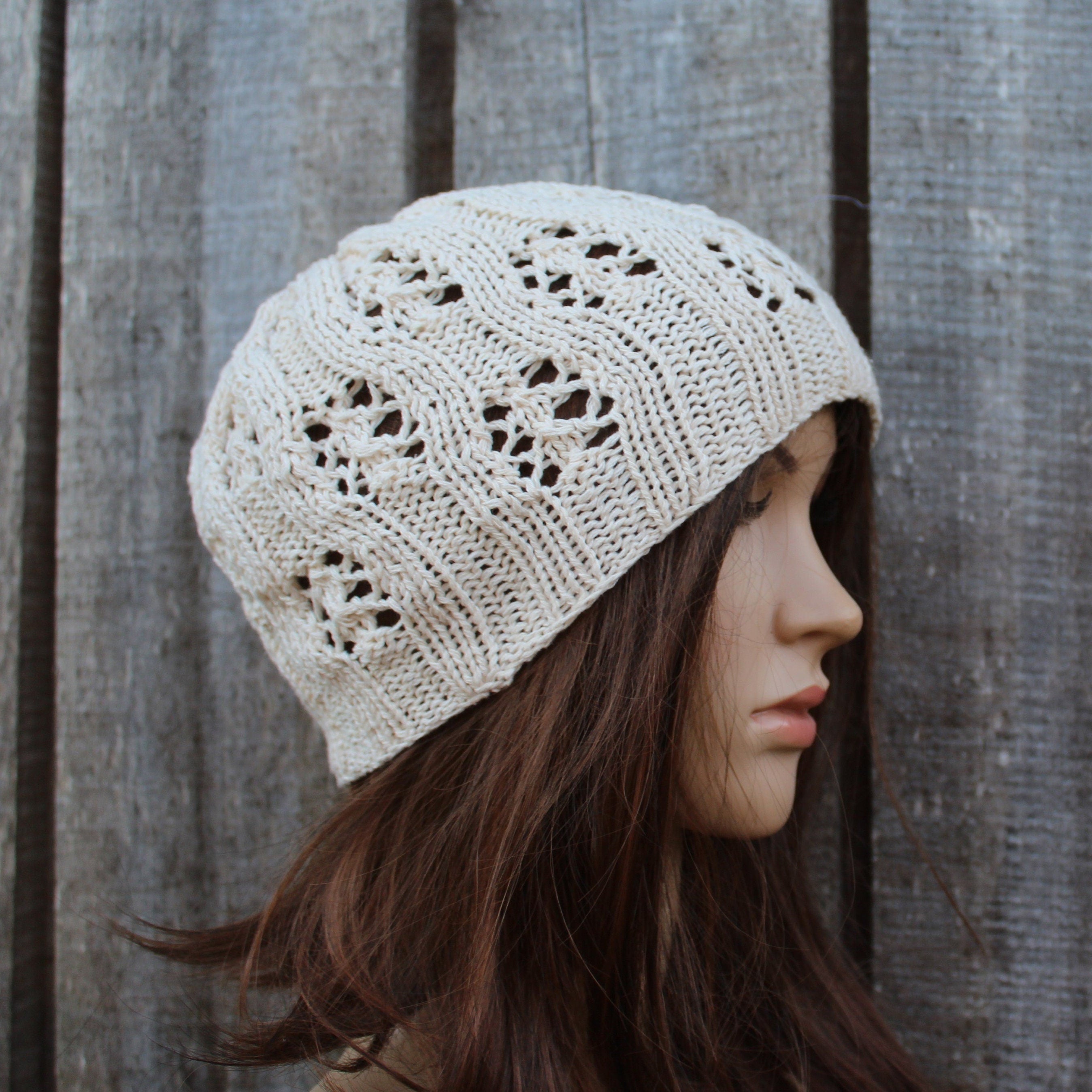 Woman wearing a beige knitted hat against a wooden fence background