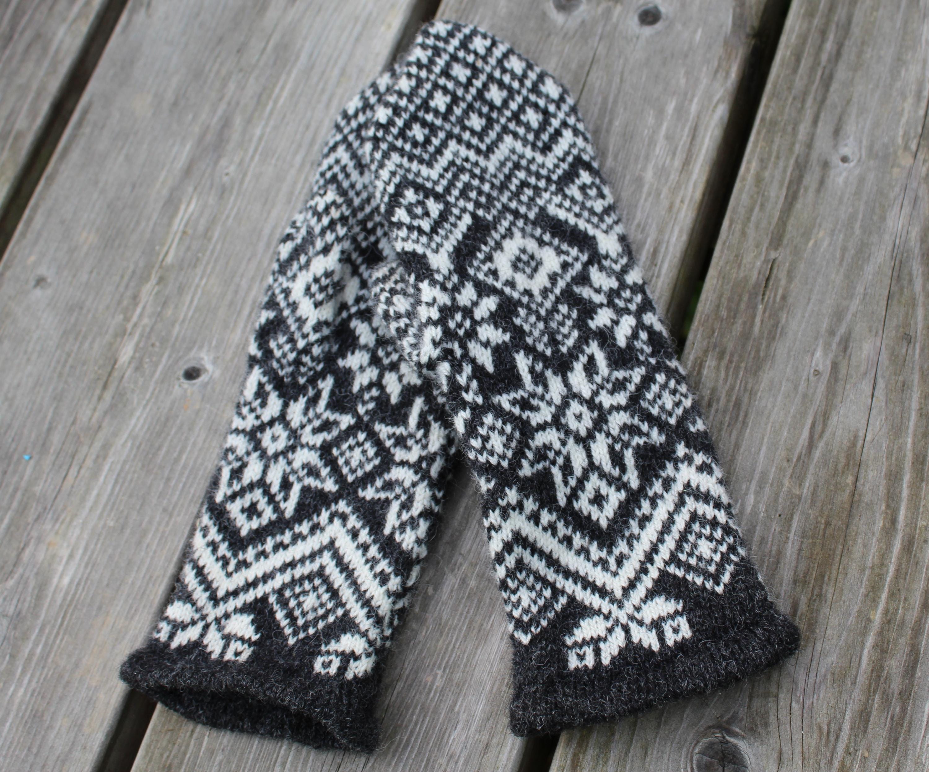 Pair of knitted mittens with a geometric pattern on a wooden surface