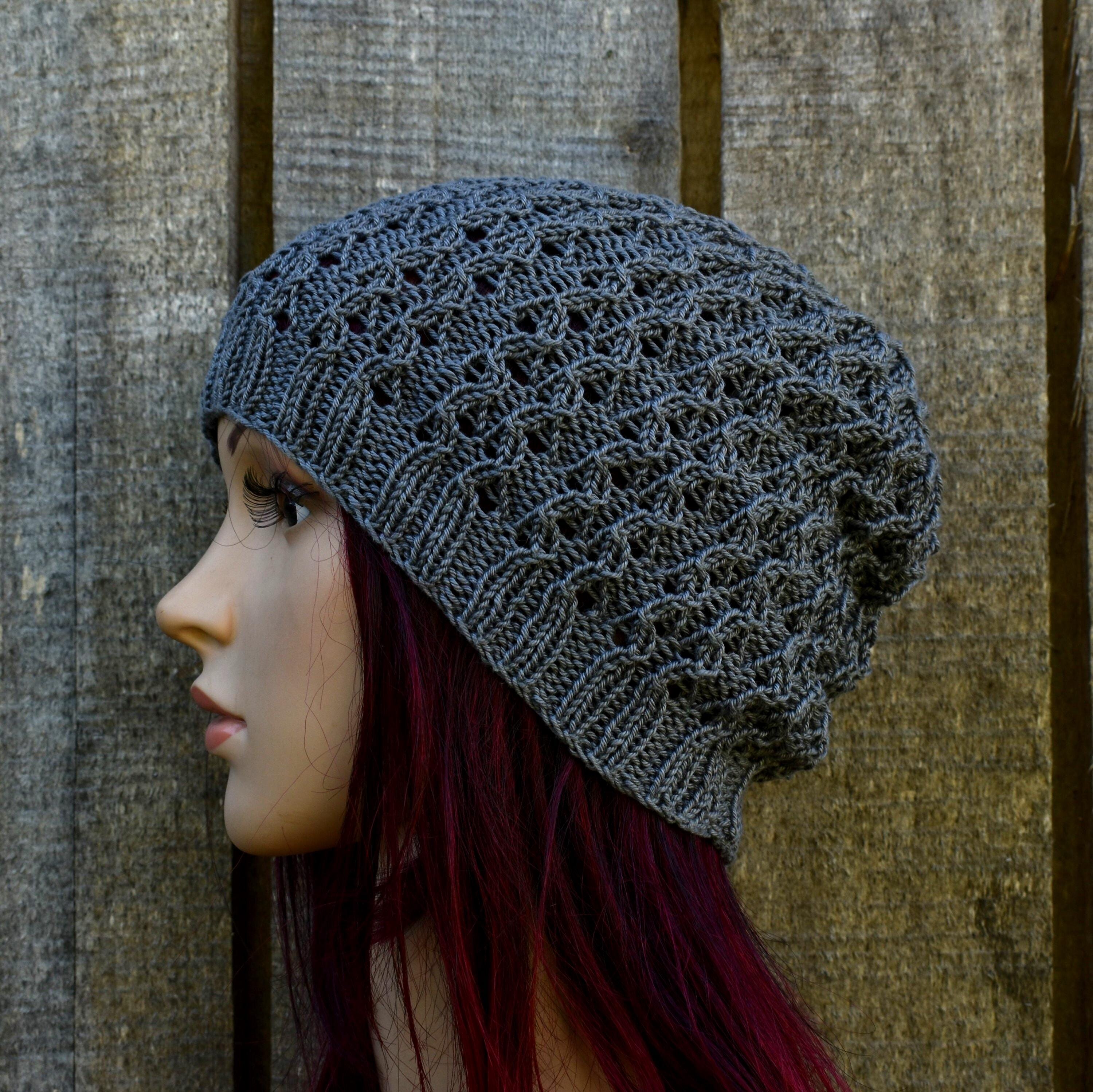 Mannequin head wearing a gray knit beanie against a textured brown background