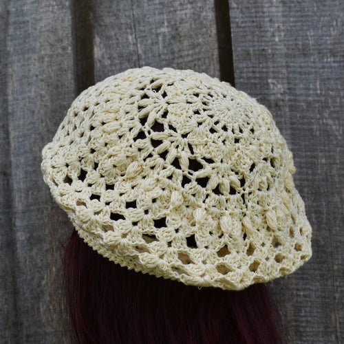 Crocheted beige hat against a wooden background