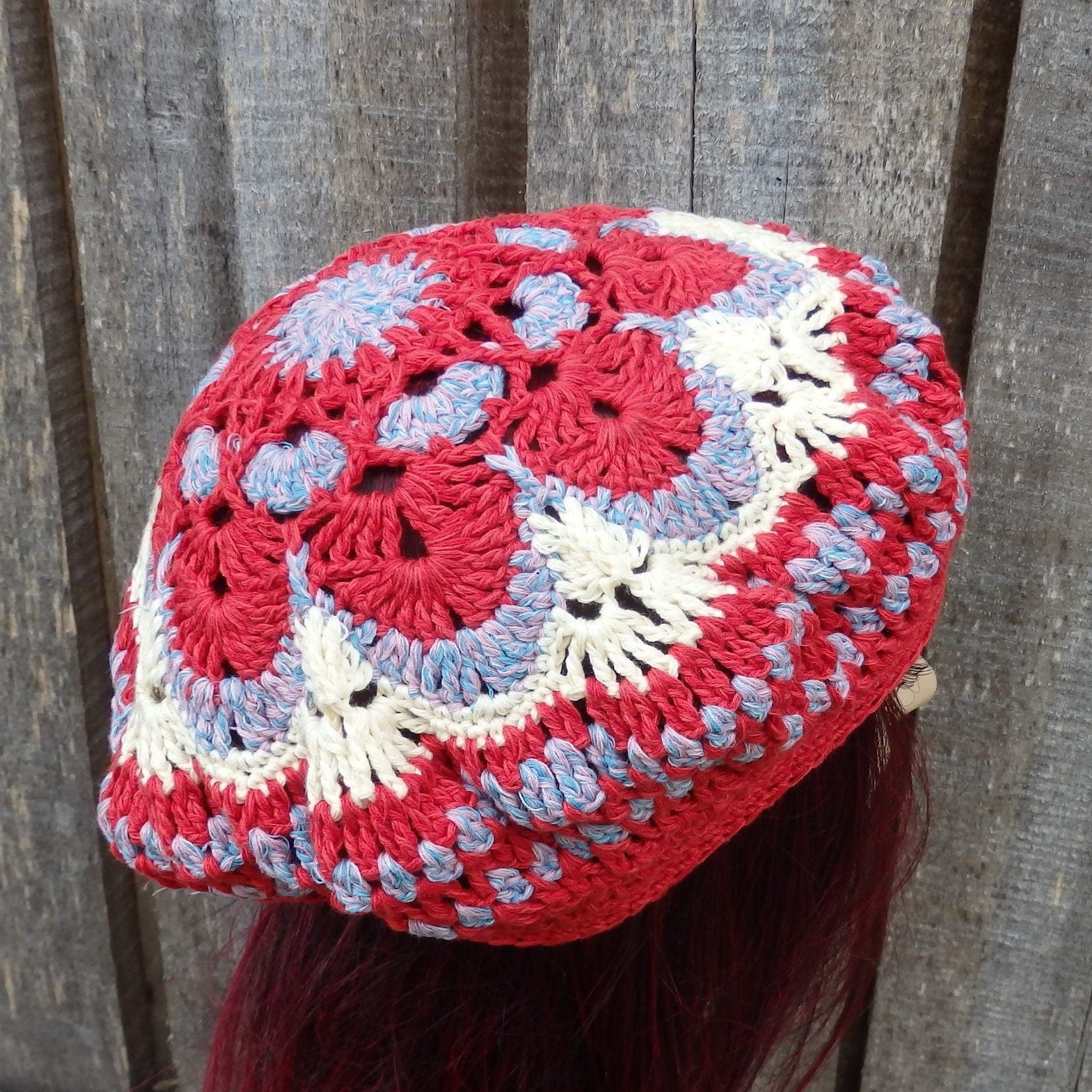 Colorful crocheted hat with red, white, and blue patterns on a wooden background