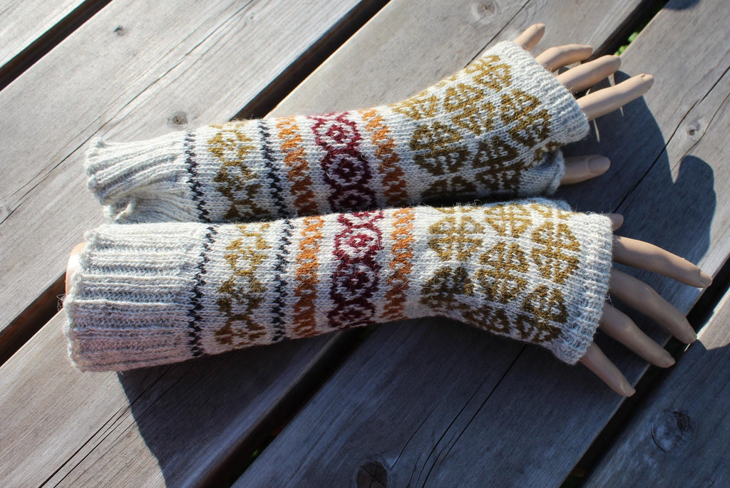 Pair of knitted fingerless gloves with a pattern on a wooden surface