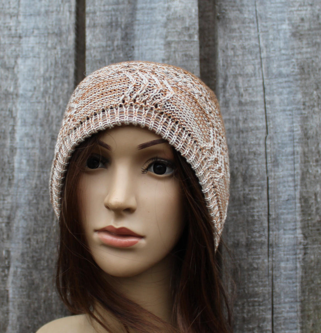 Knitted beige hat on a mannequin head against a textured gray background