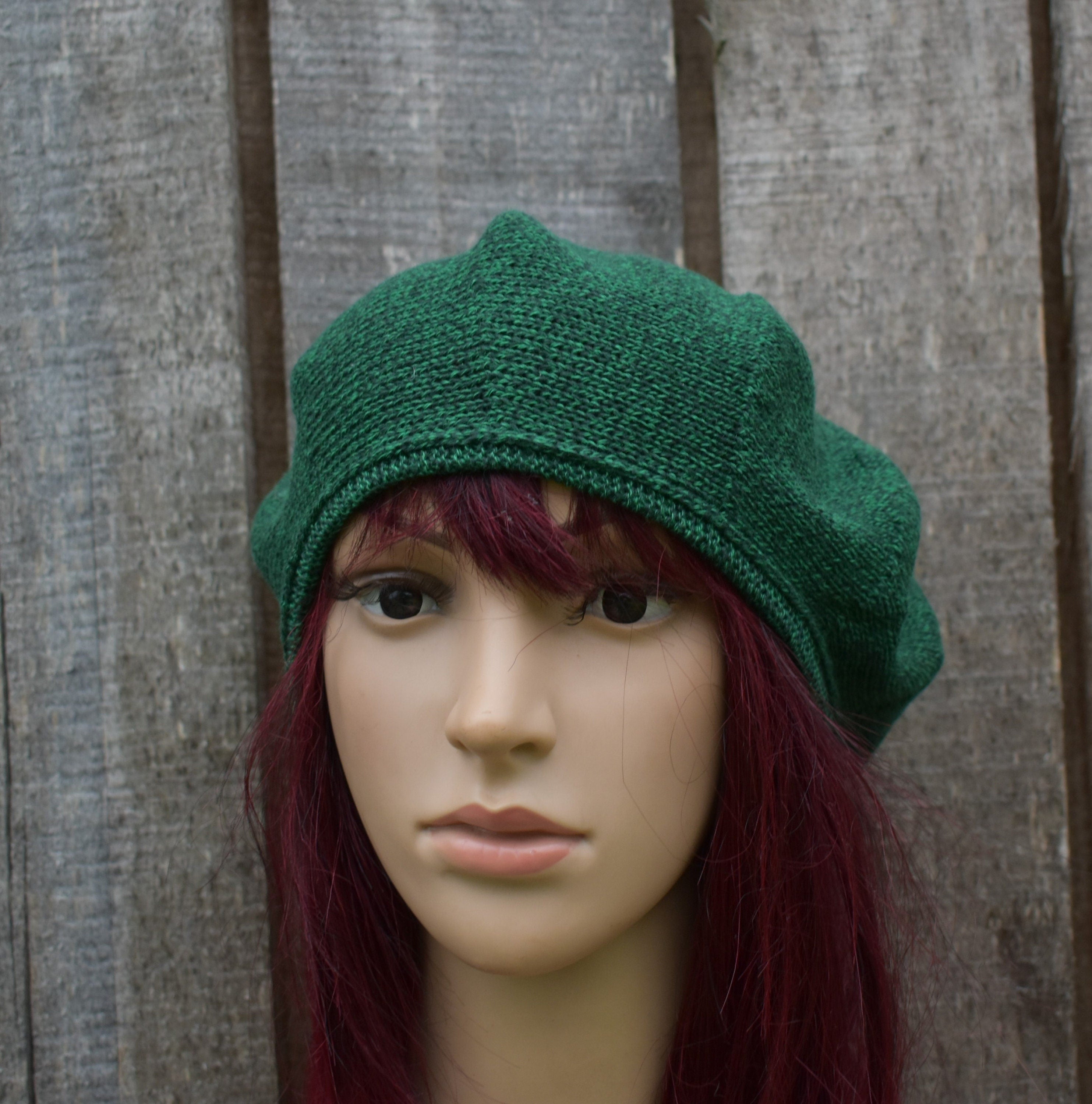 Green knitted hat on a mannequin head against a wooden background
