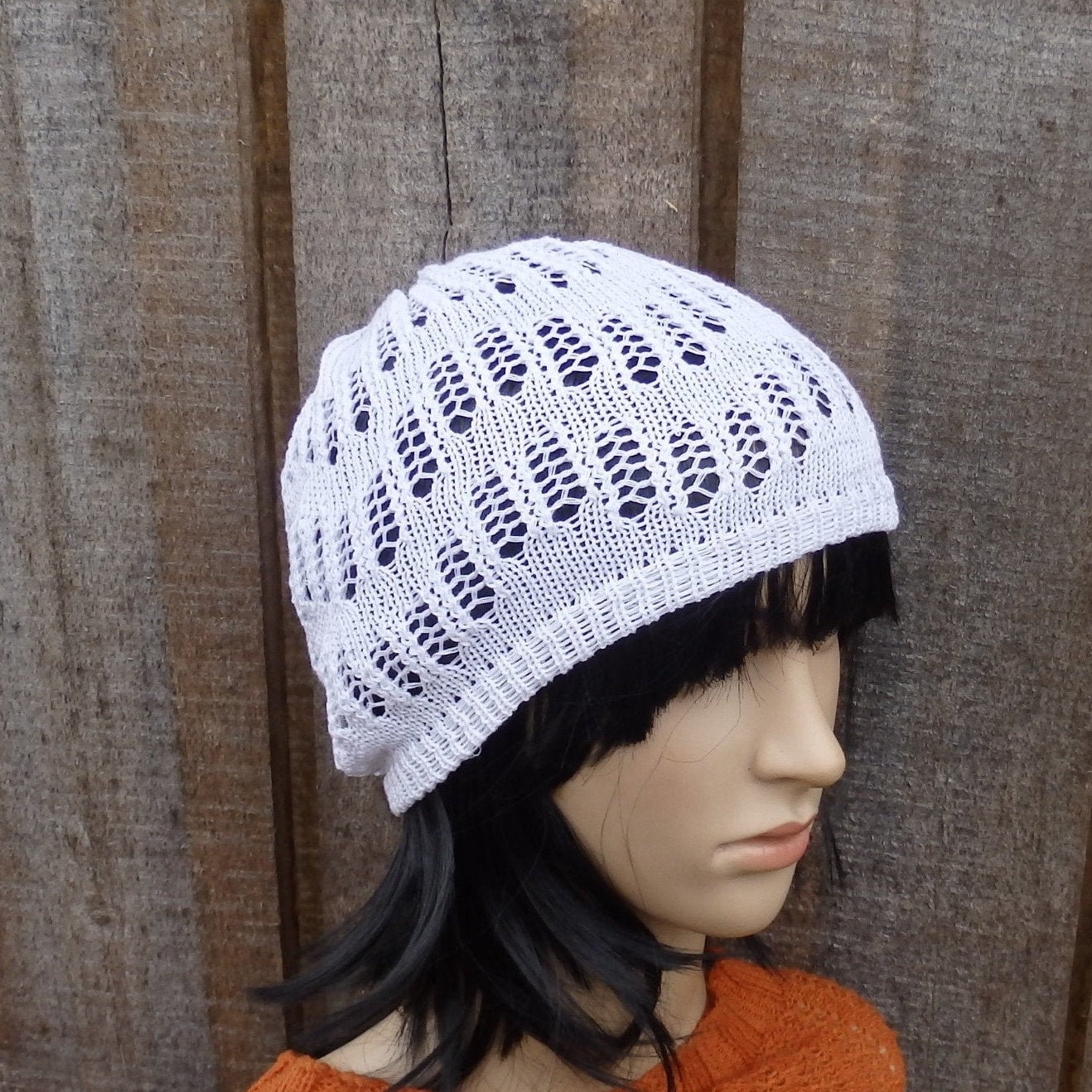 White knitted hat on a mannequin head against a wooden background