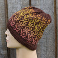 Knitted hat with a pattern on a mannequin head against a wooden background
