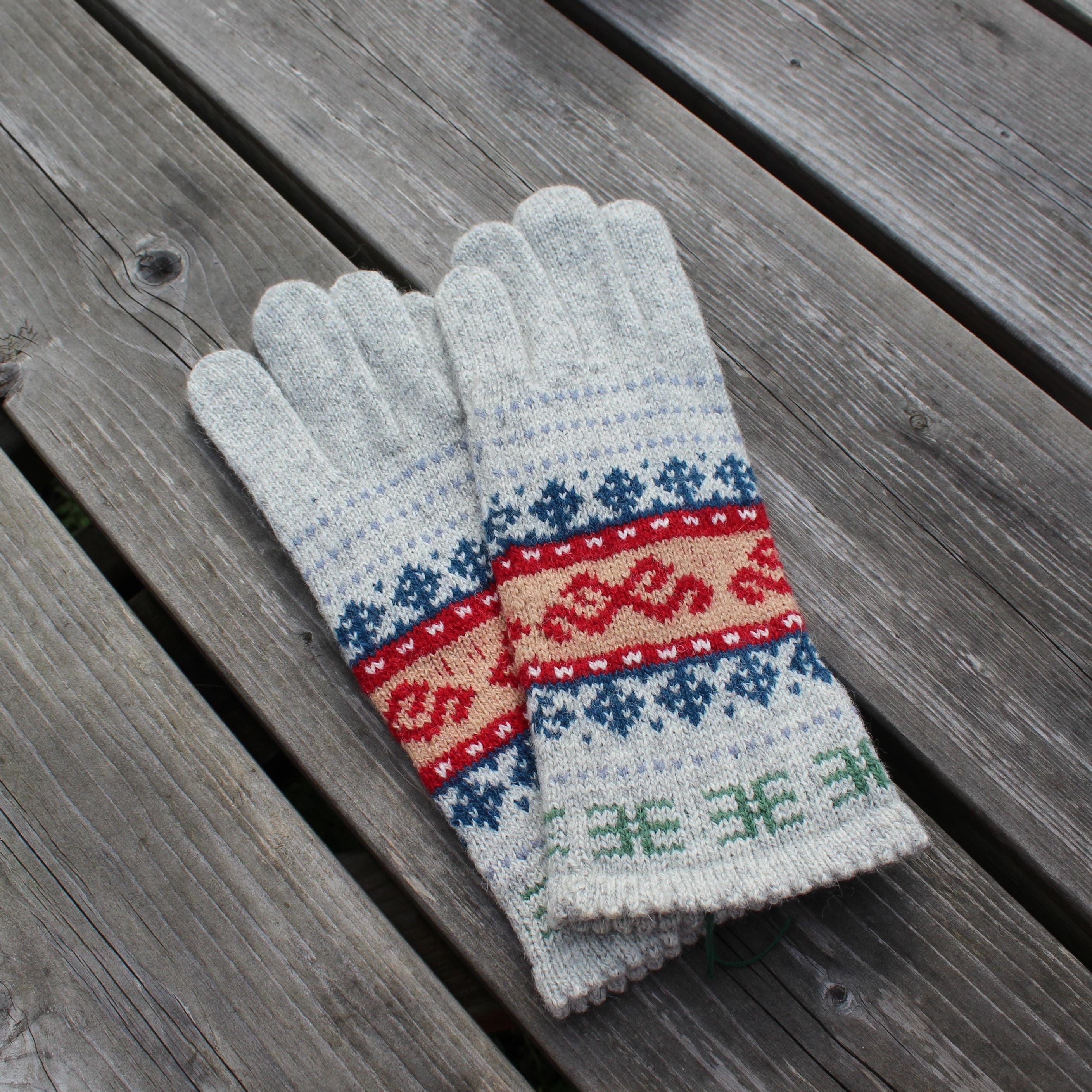 Pair of gray gloves with a colorful pattern on a wooden surface