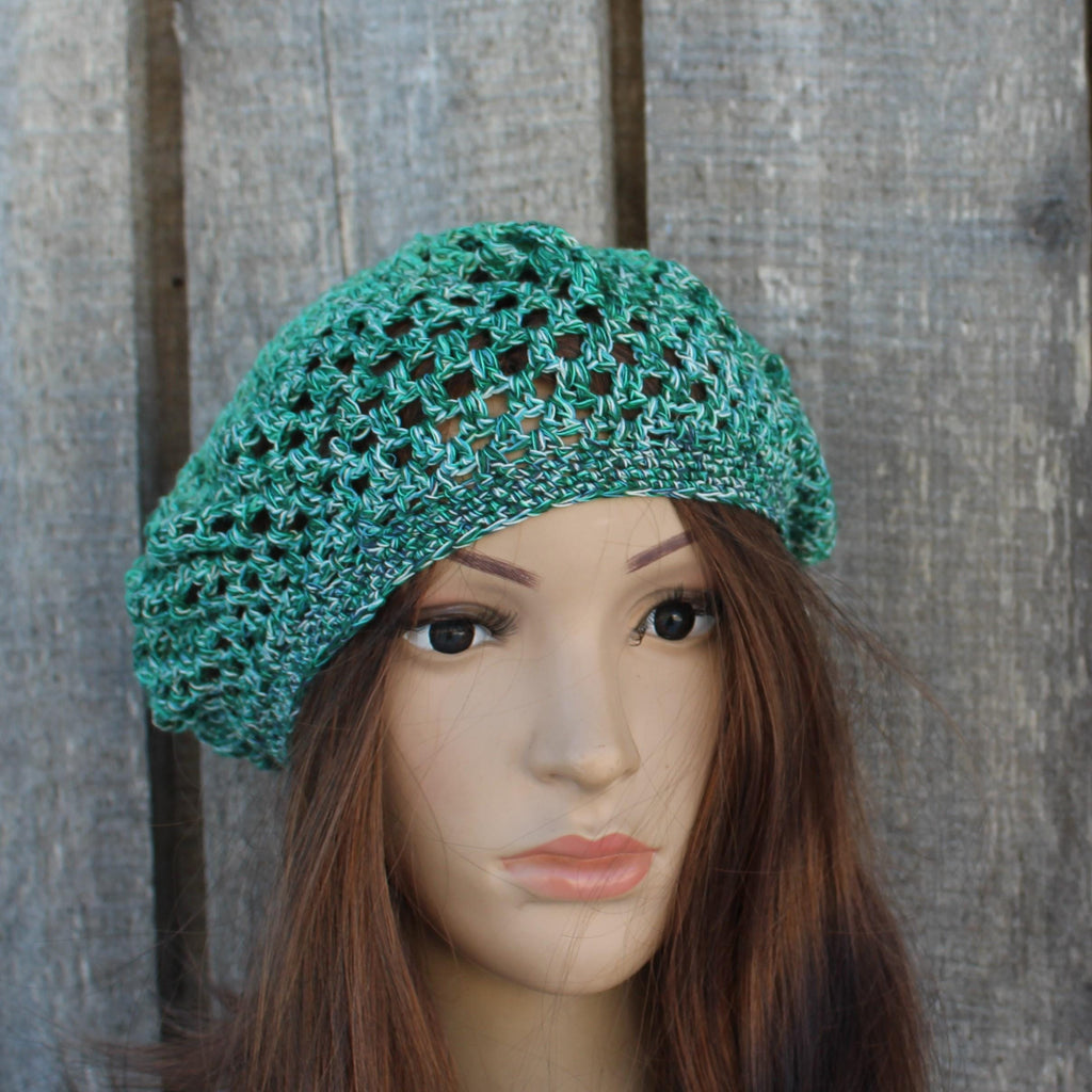 Green crochet hat on a mannequin head against a wooden background