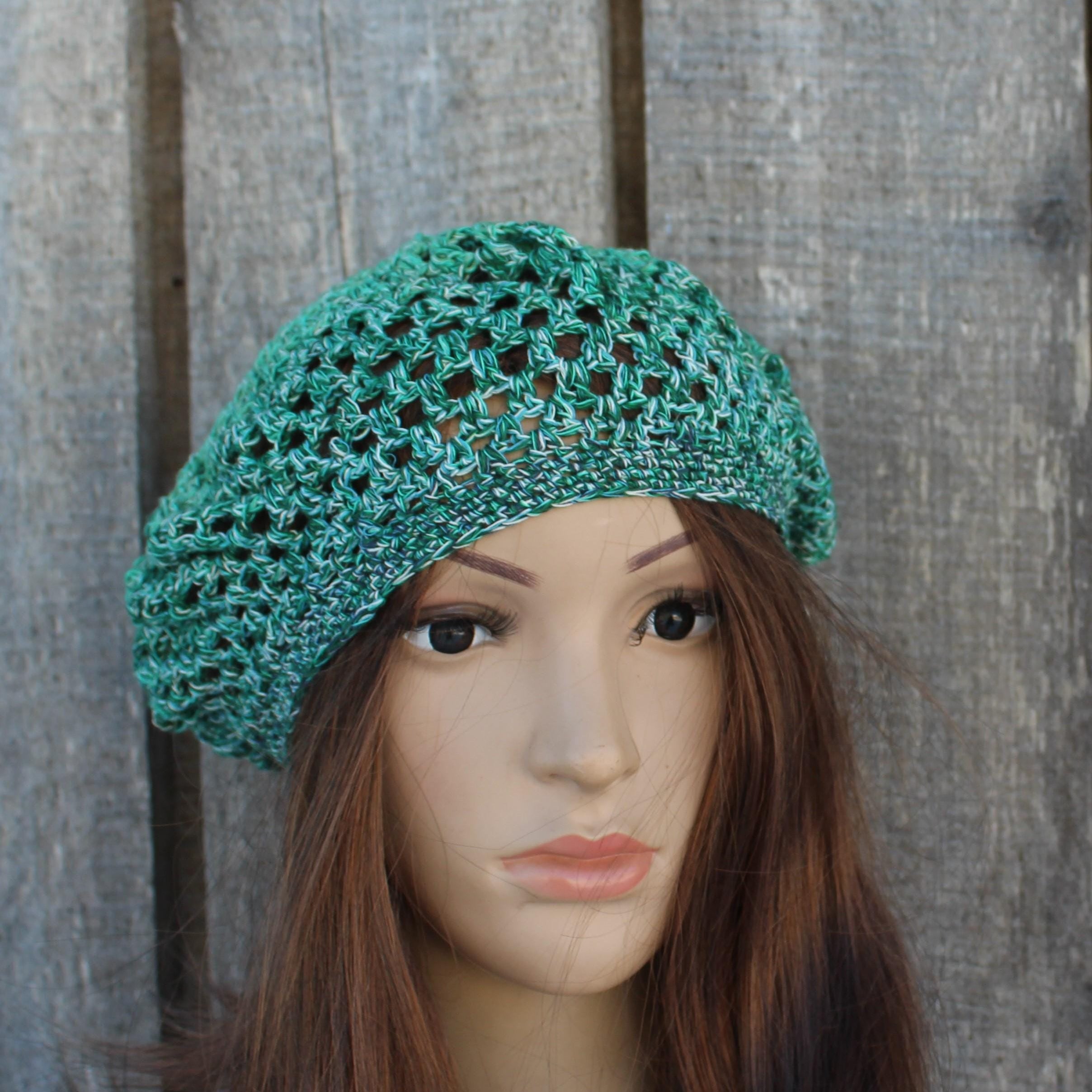 Green crochet hat on a mannequin head against a wooden background