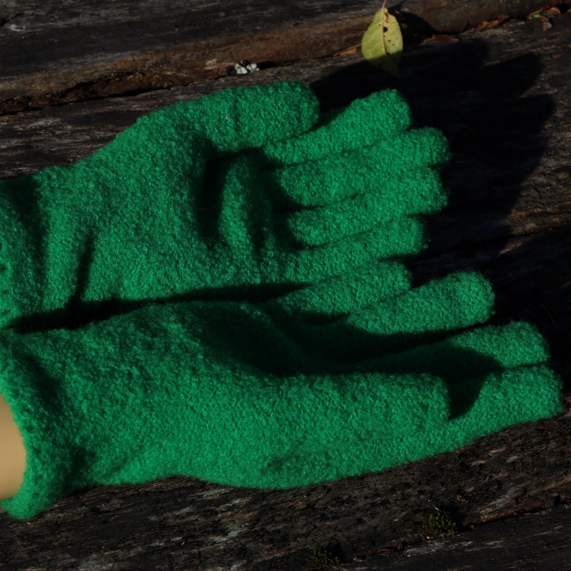 Green knitted gloves on a wooden surface